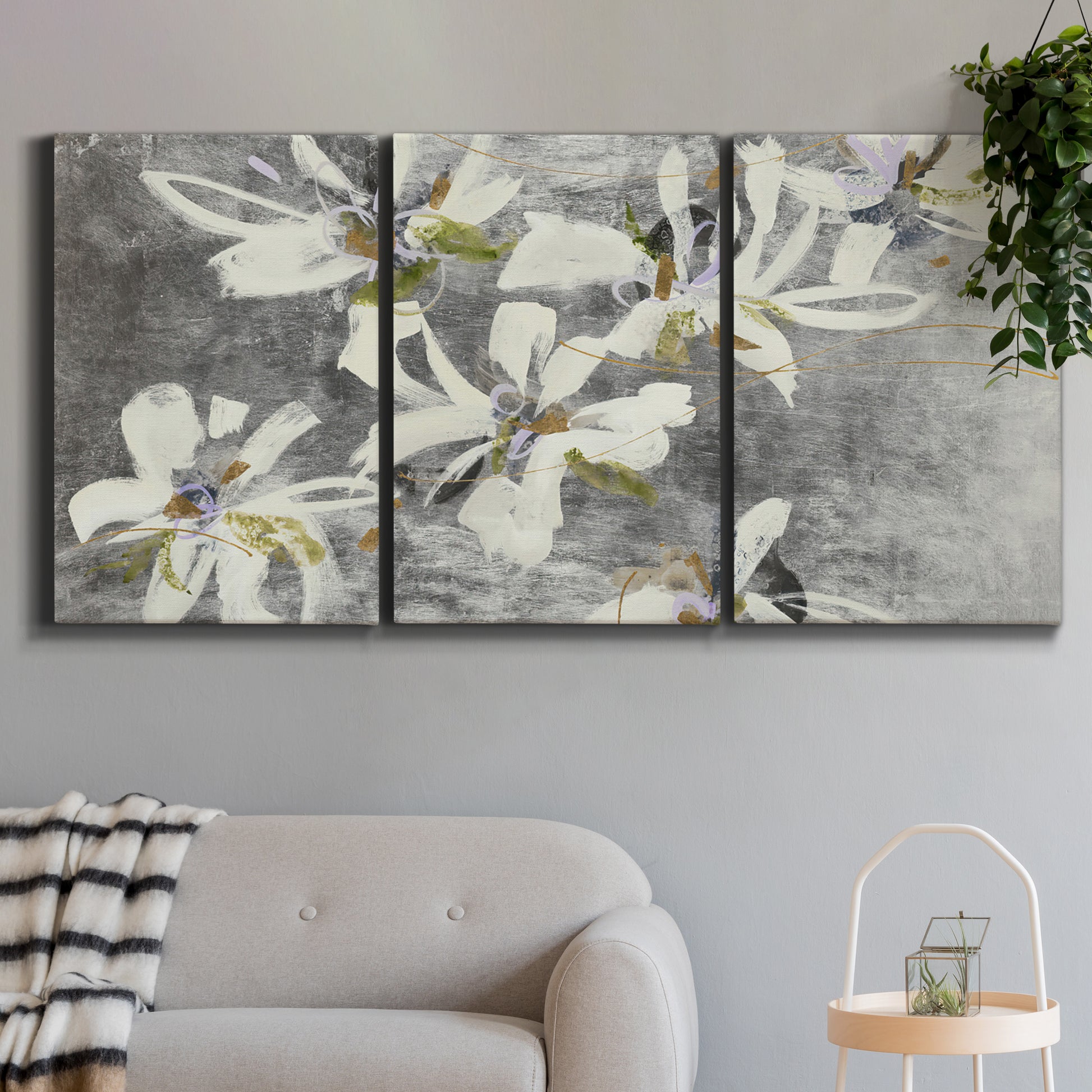 Three-panel canvas wall art featuring delicate floral symbolic arrangement, displayed in a modern living room above a sofa.