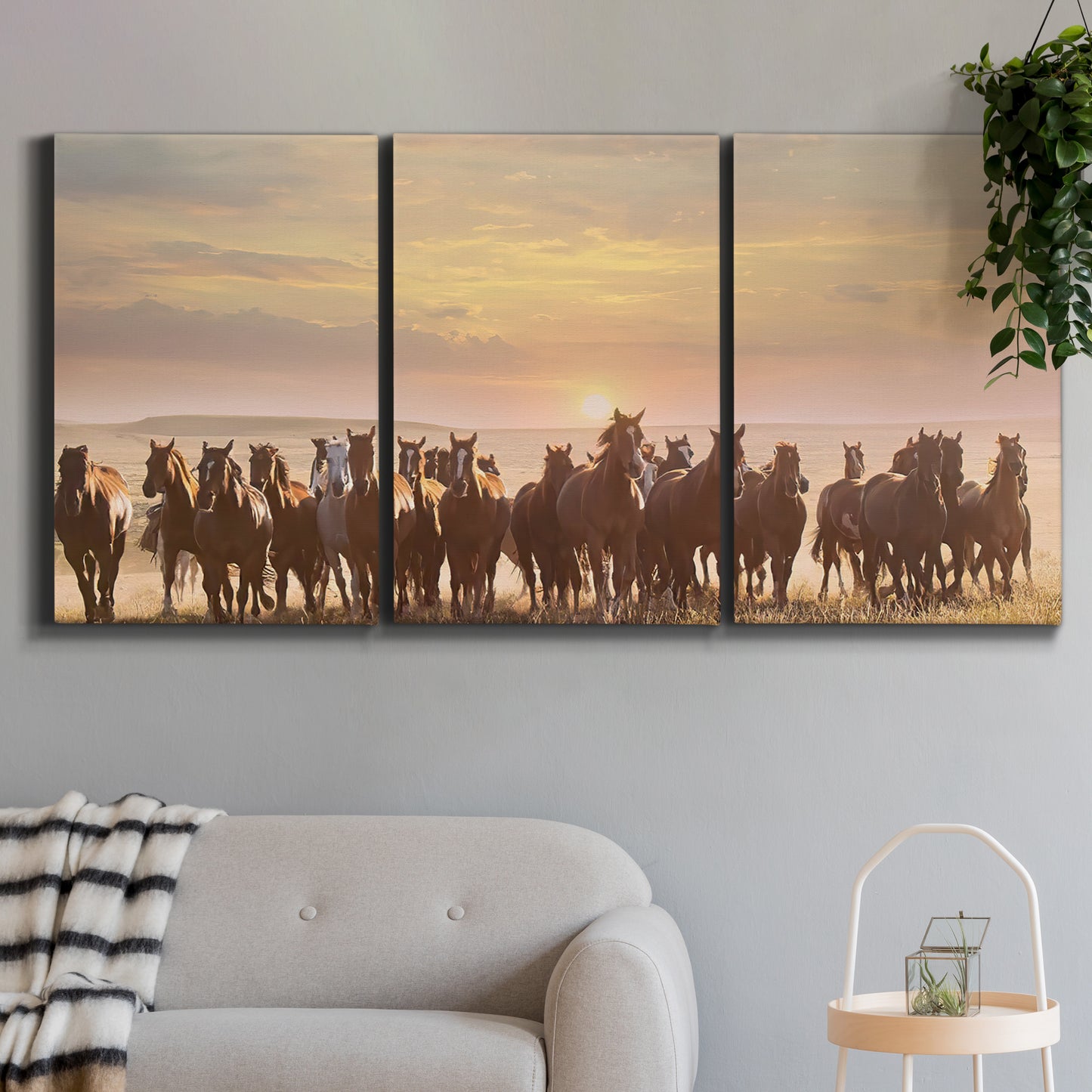 Three-panel canvas wall art featuring running horses captured in motion, displayed in a modern living room above a sofa.