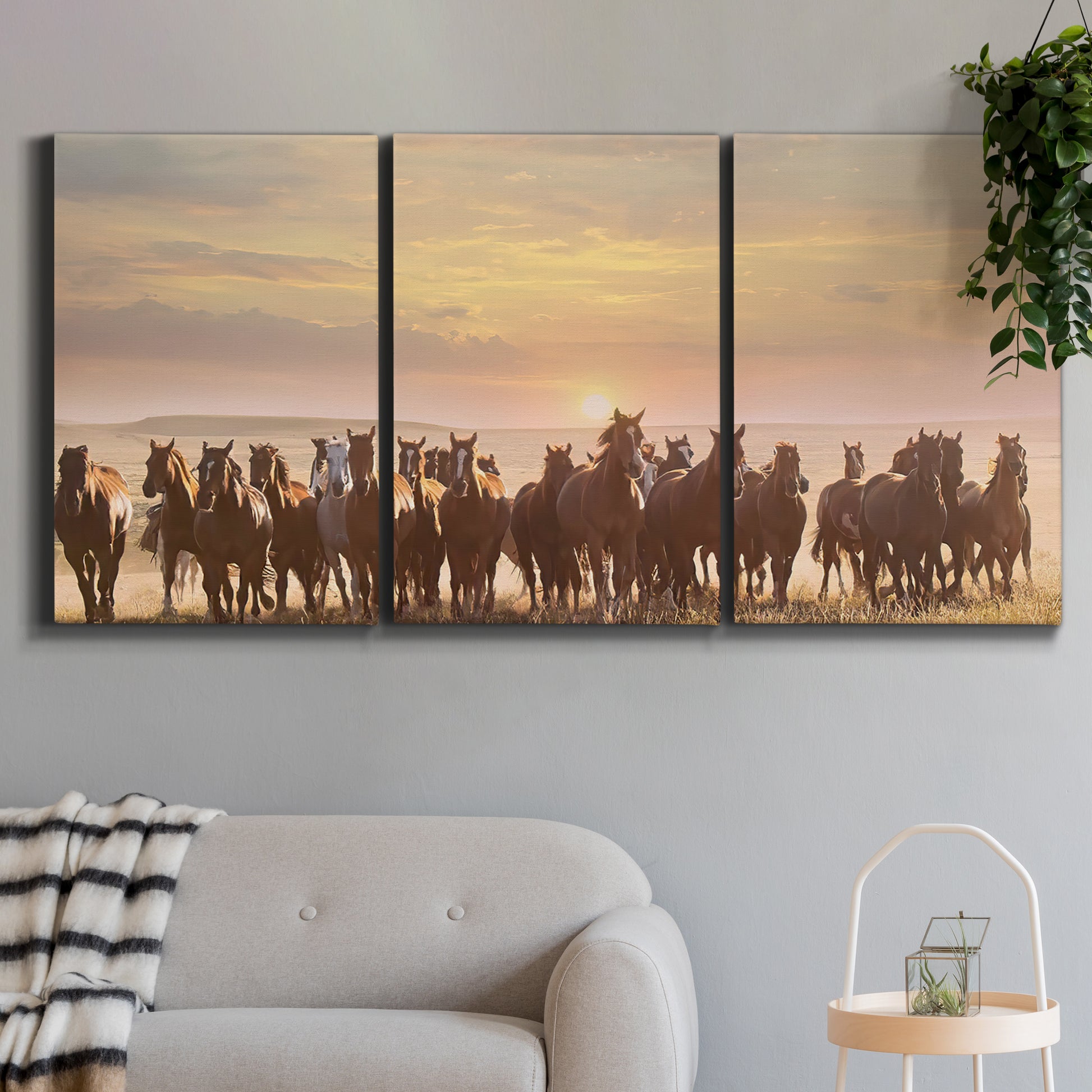 Three-panel canvas wall art featuring running horses captured in motion, displayed in a modern living room above a sofa.