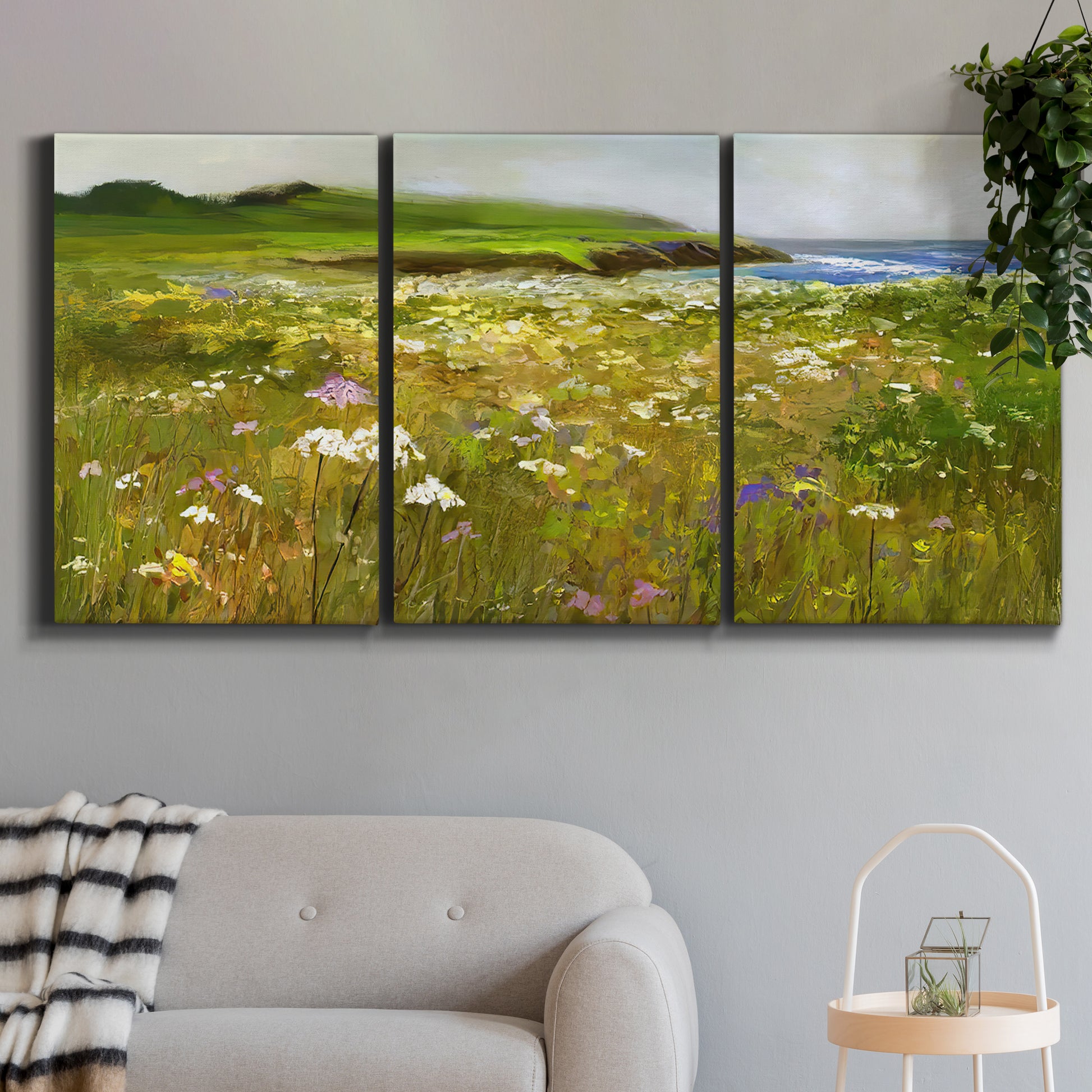 Three-panel canvas wall art featuring rugged coastal cliff landscape, displayed in a modern living room above a sofa.