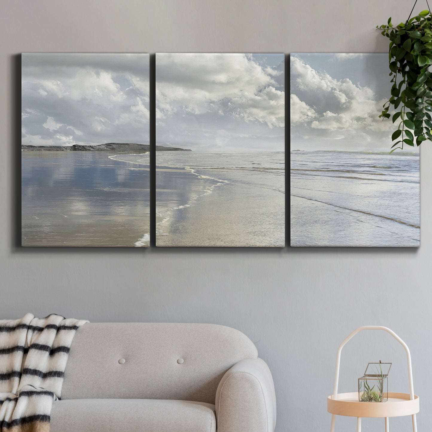 Three-panel canvas wall art featuring endless beach meeting ocean horizon, displayed in a modern living room above a sofa.