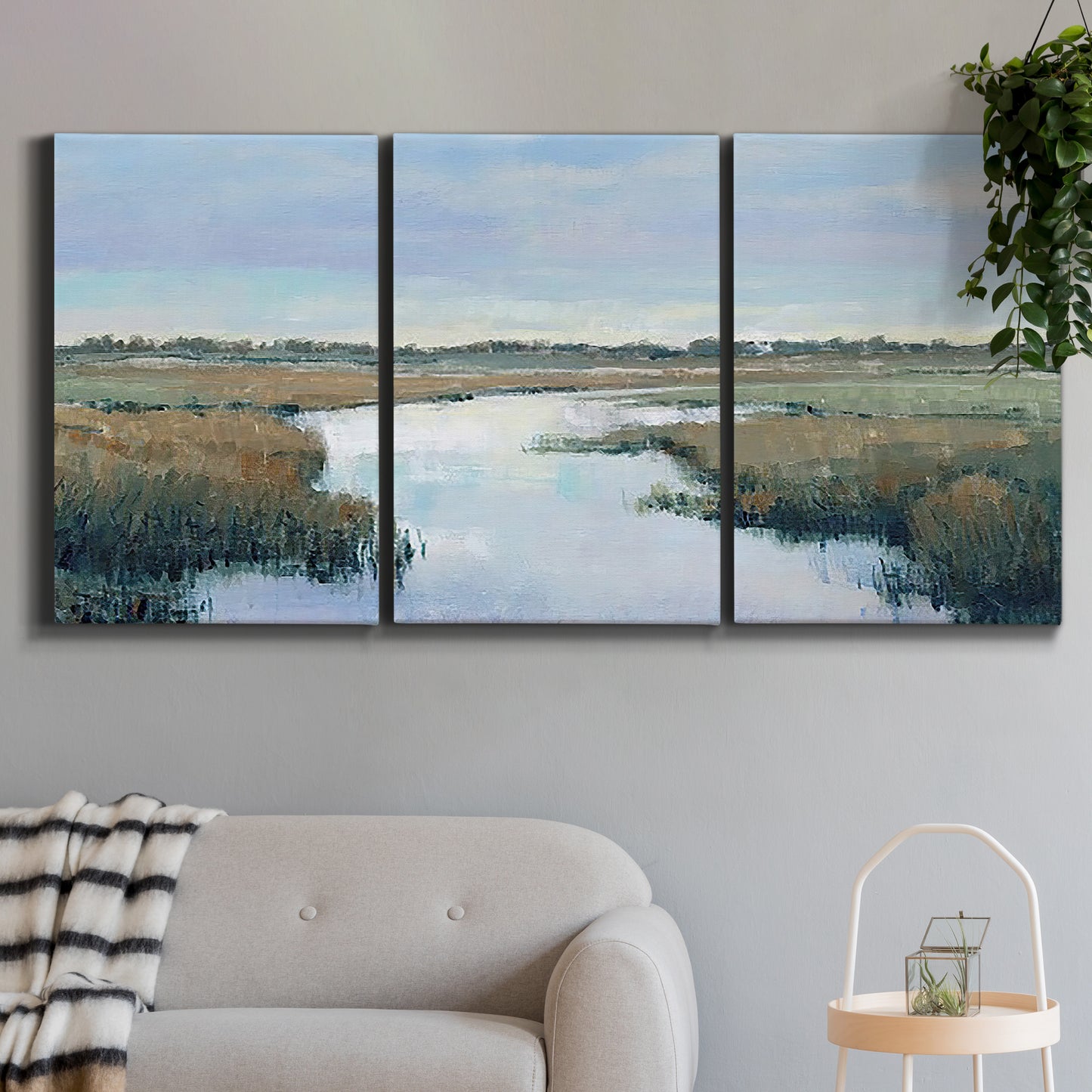 Three-panel canvas wall art featuring coastal plain with layered horizon, displayed in a modern living room above a sofa.