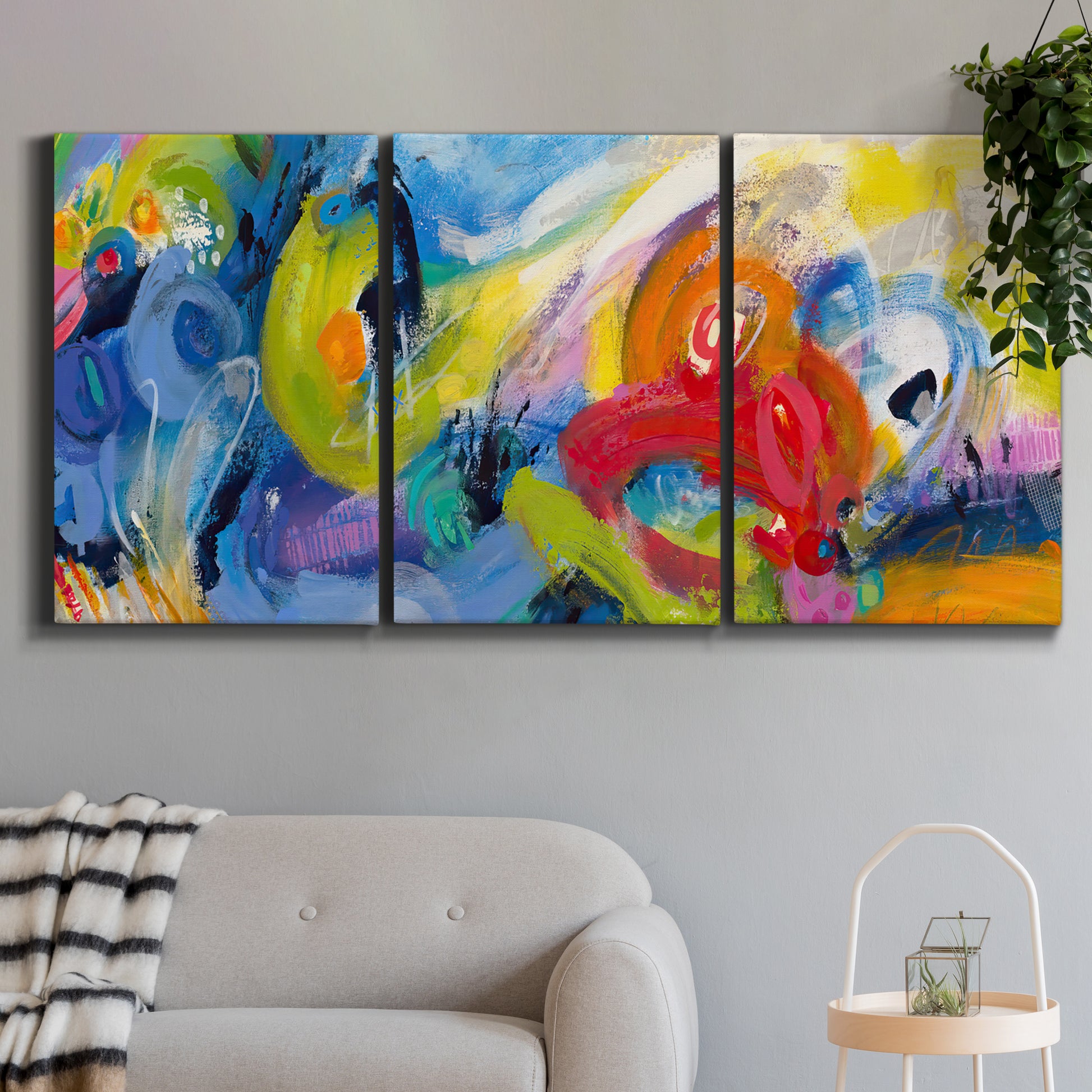 Three-panel canvas wall art featuring colorful abstract racing forms, displayed in a modern living room above a sofa.