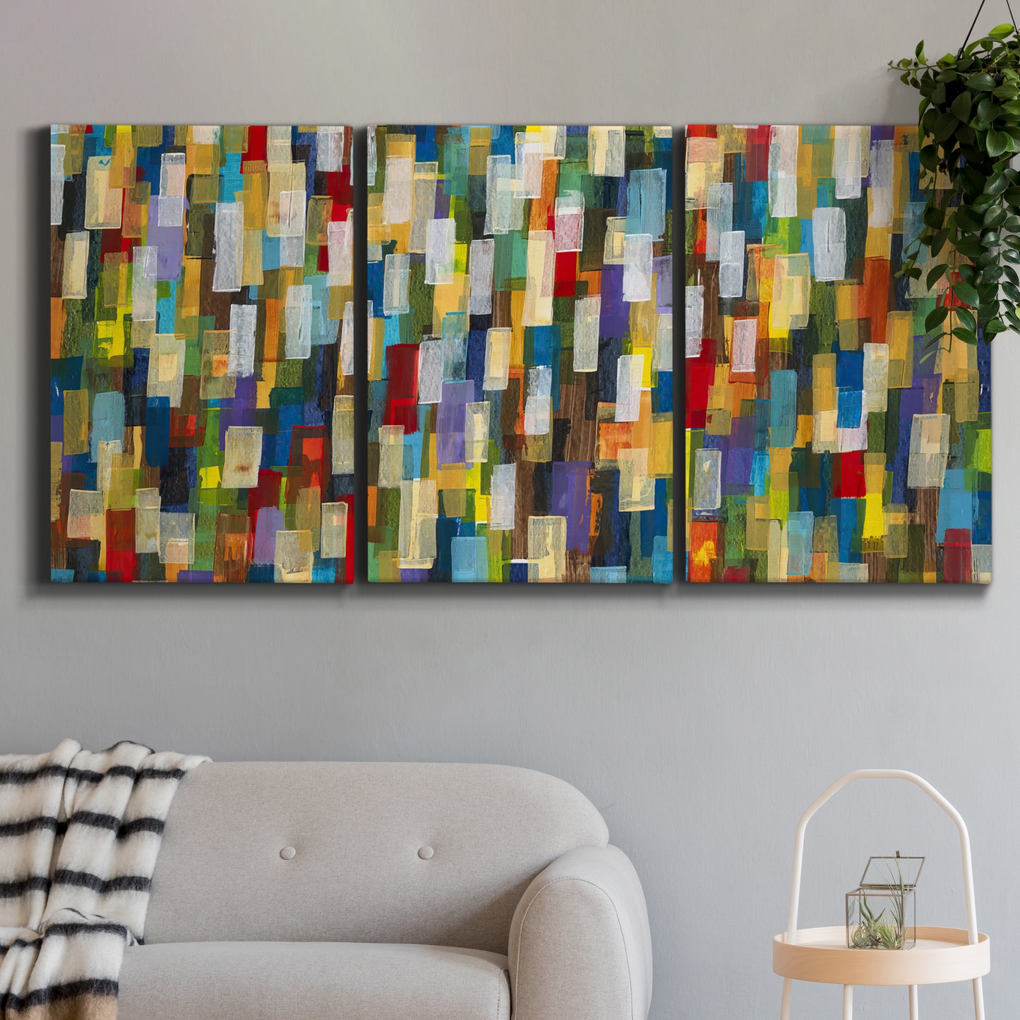 Three-panel canvas wall art featuring colorful confetti style abstraction, displayed in a modern living room above a sofa.