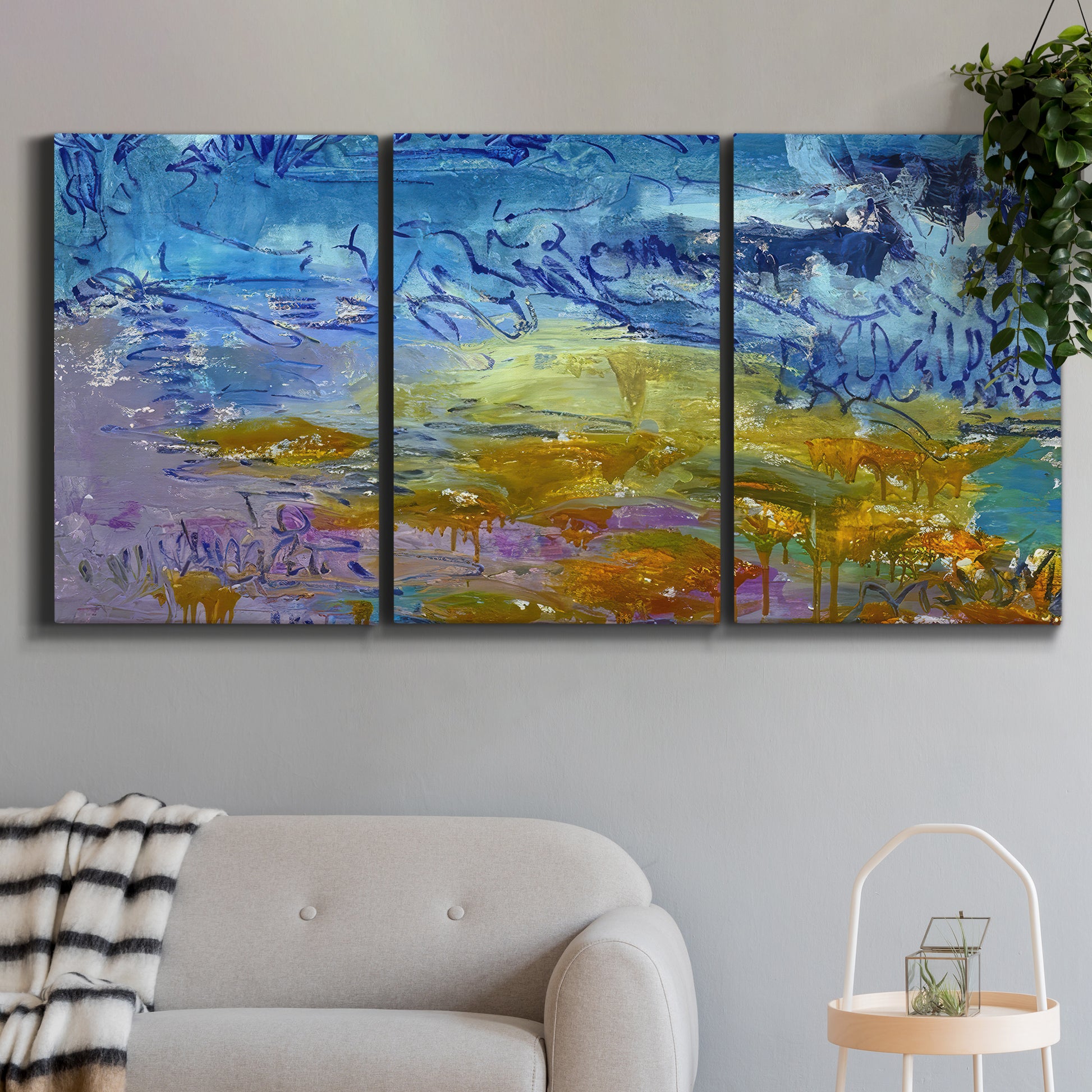 Three-panel canvas wall art featuring expressive abstract with layered color, displayed in a modern living room above a sofa.