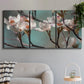 Three-panel canvas wall art featuring dogwood blossoms in spring photograph, displayed in a modern living room above a sofa.