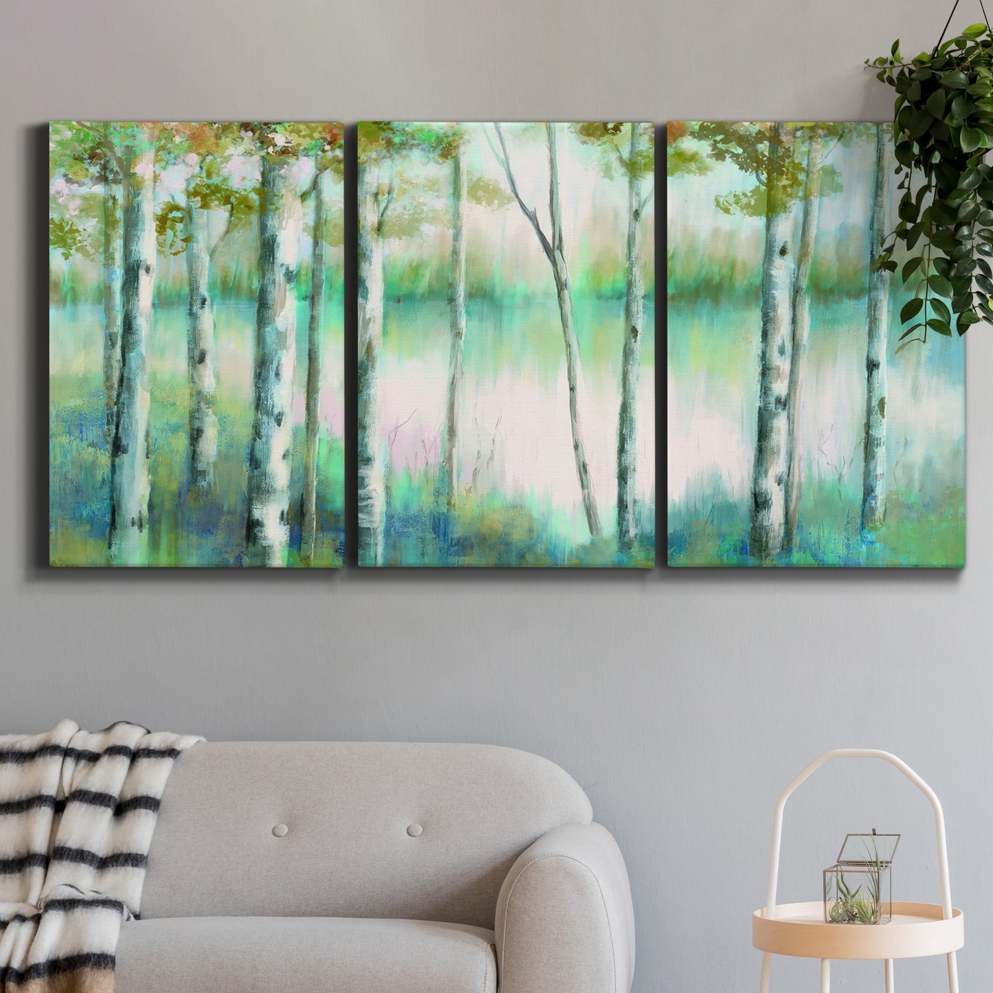 Three-panel canvas wall art featuring calm lake framed by aspen trees, displayed in a modern living room above a sofa.