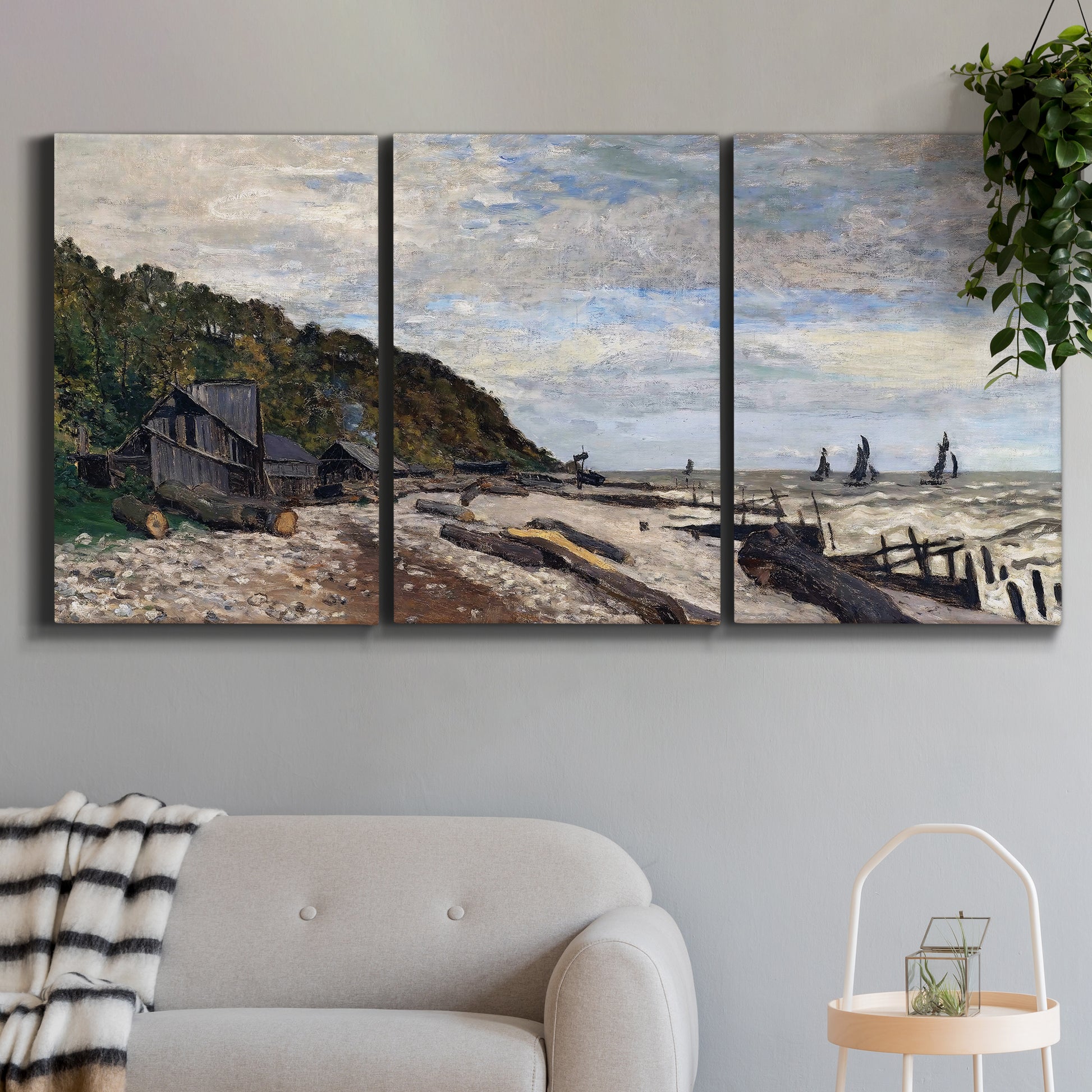 Three-panel canvas wall art featuring open sea along rocky shore, displayed in a modern living room above a sofa.