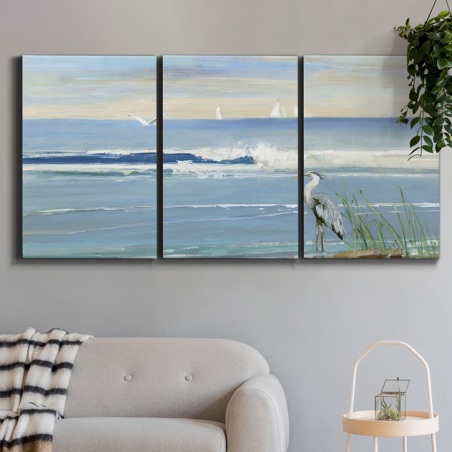 Three-panel canvas wall art featuring sunrise reflecting across bay waters, displayed in a modern living room above a sofa.