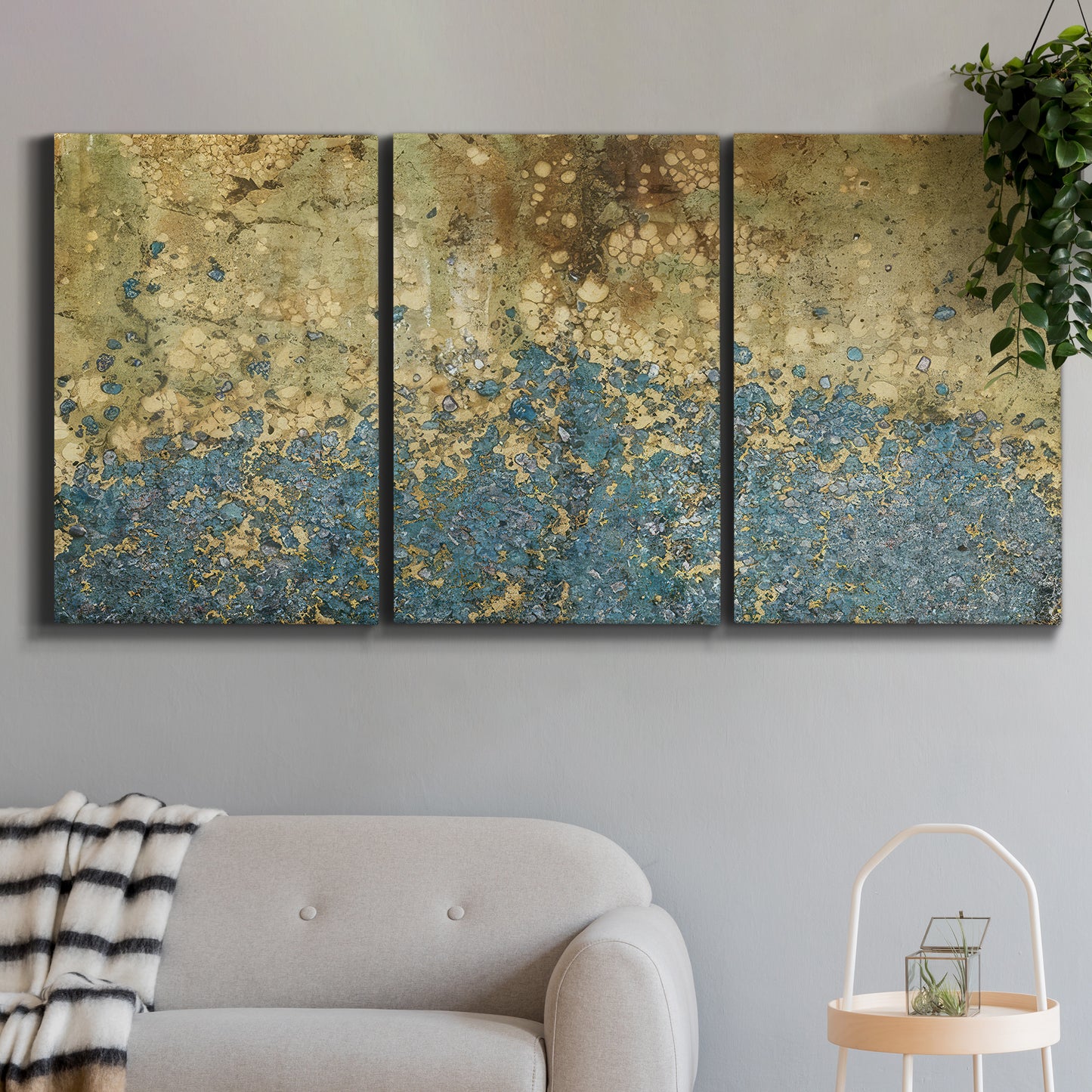 Three-panel canvas wall art featuring metallic abstract gold tones, displayed in a modern living room above a sofa.