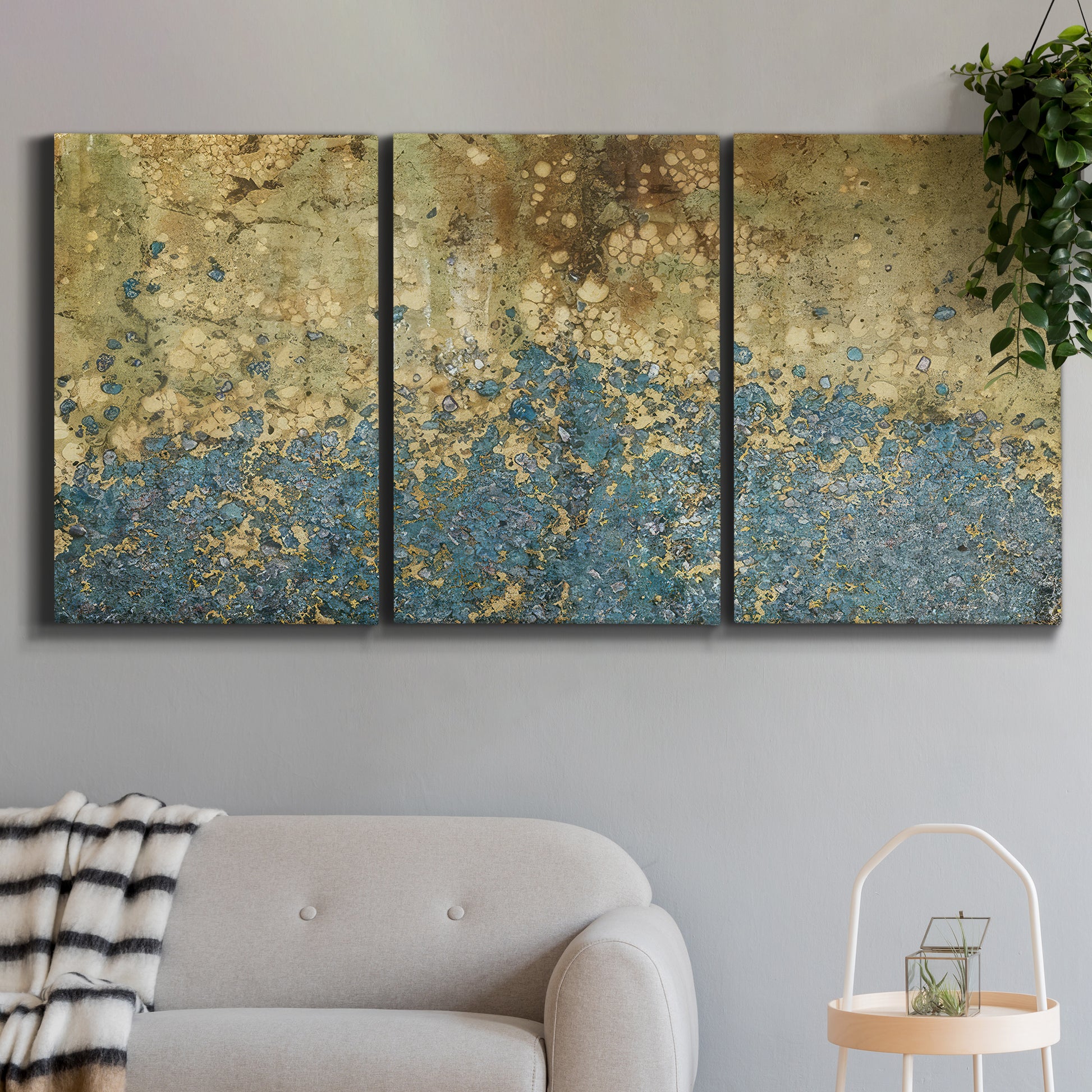 Three-panel canvas wall art featuring metallic abstract gold tones, displayed in a modern living room above a sofa.