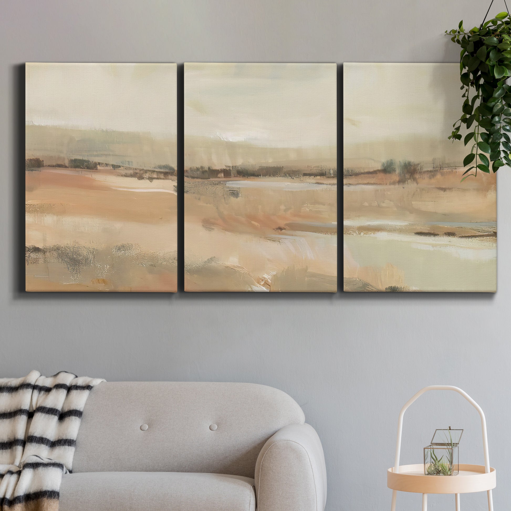 Three-panel canvas wall art featuring earth toned abstract landscape, displayed in a modern living room above a sofa.