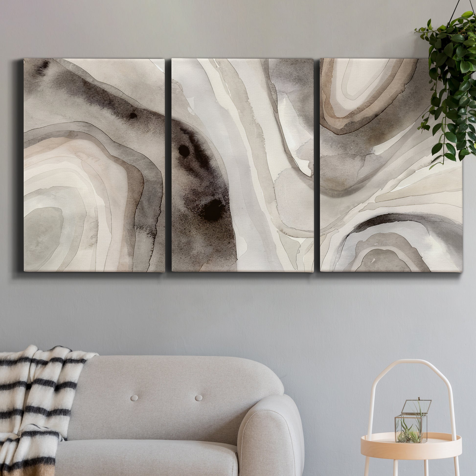 Three-panel canvas wall art featuring layered stone inspired abstract forms, displayed in a modern living room above a sofa.