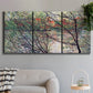 Three-panel canvas wall art featuring riverside park with figures and trees, displayed in a modern living room above a sofa.