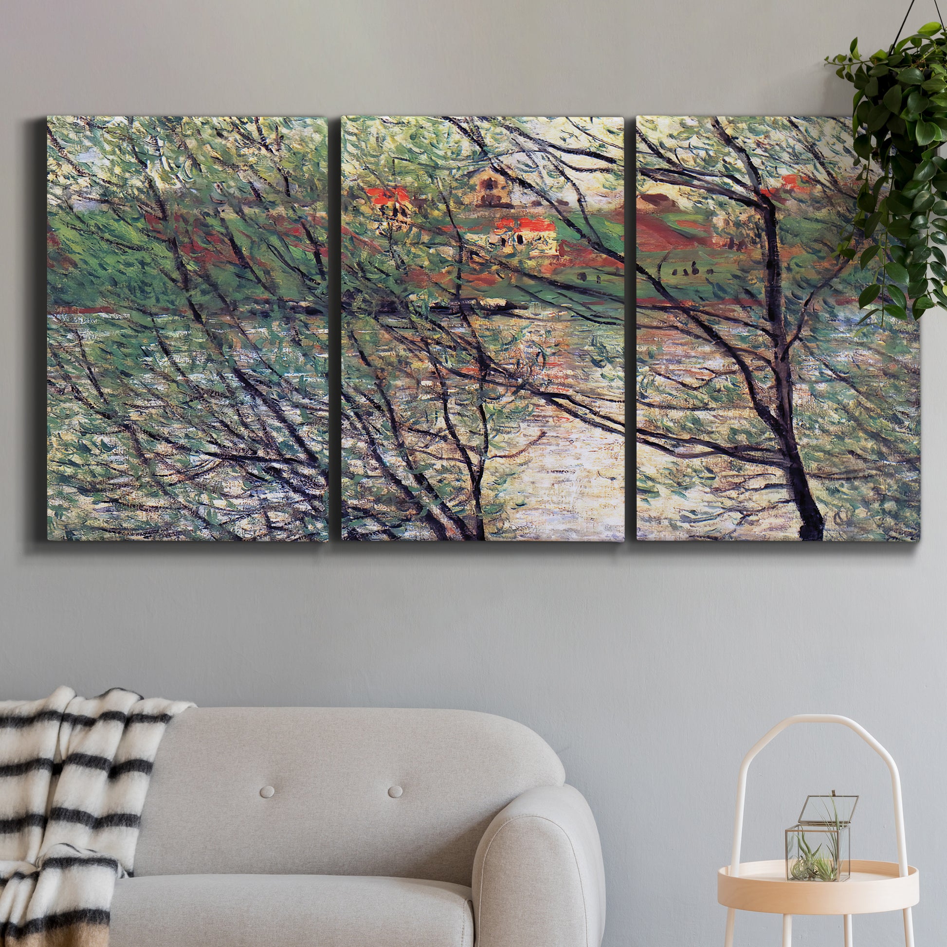 Three-panel canvas wall art featuring riverside park with figures and trees, displayed in a modern living room above a sofa.