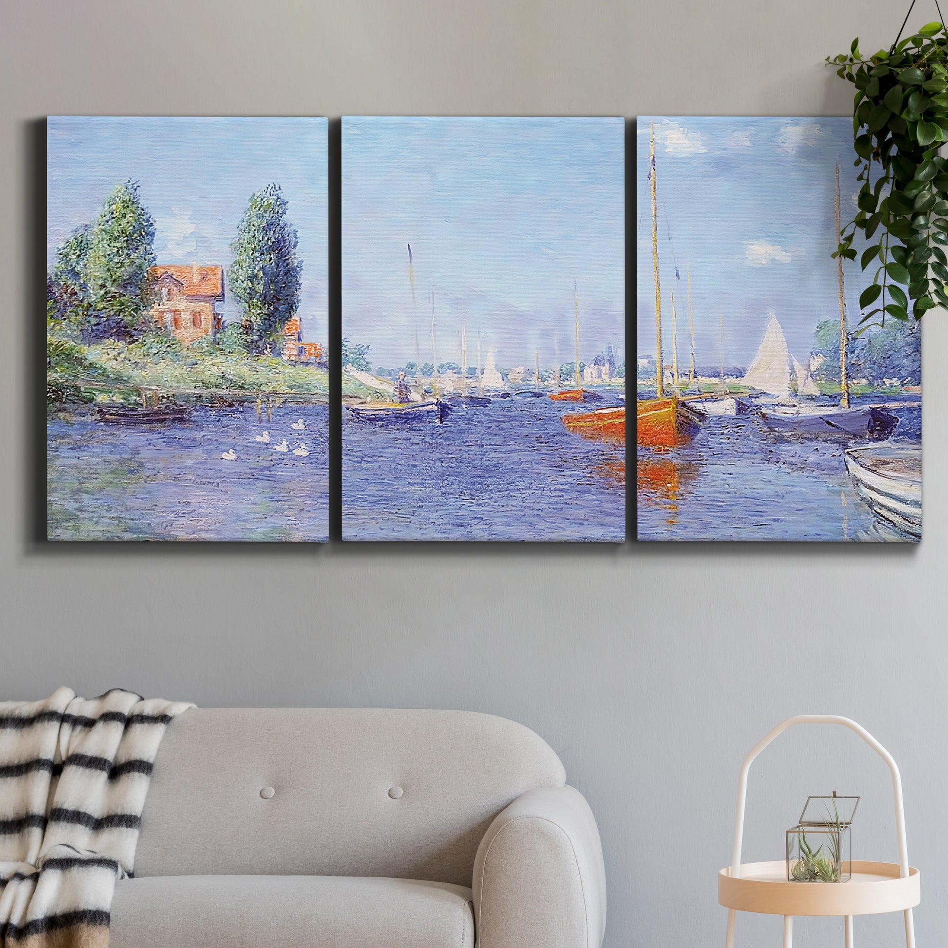 Three-panel canvas wall art featuring river flowing past riverside town, displayed in a modern living room above a sofa.
