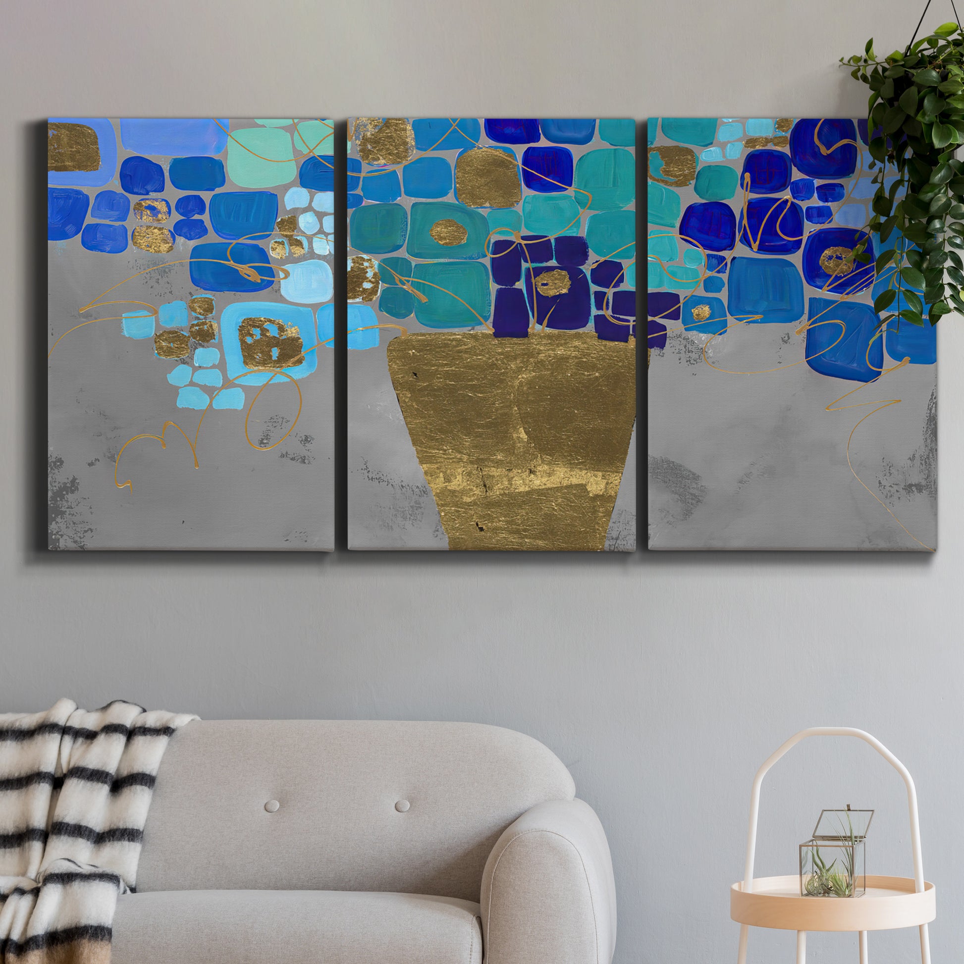 Three-panel canvas wall art featuring blue floral abstract botanical expression, displayed in a modern living room above a sofa.