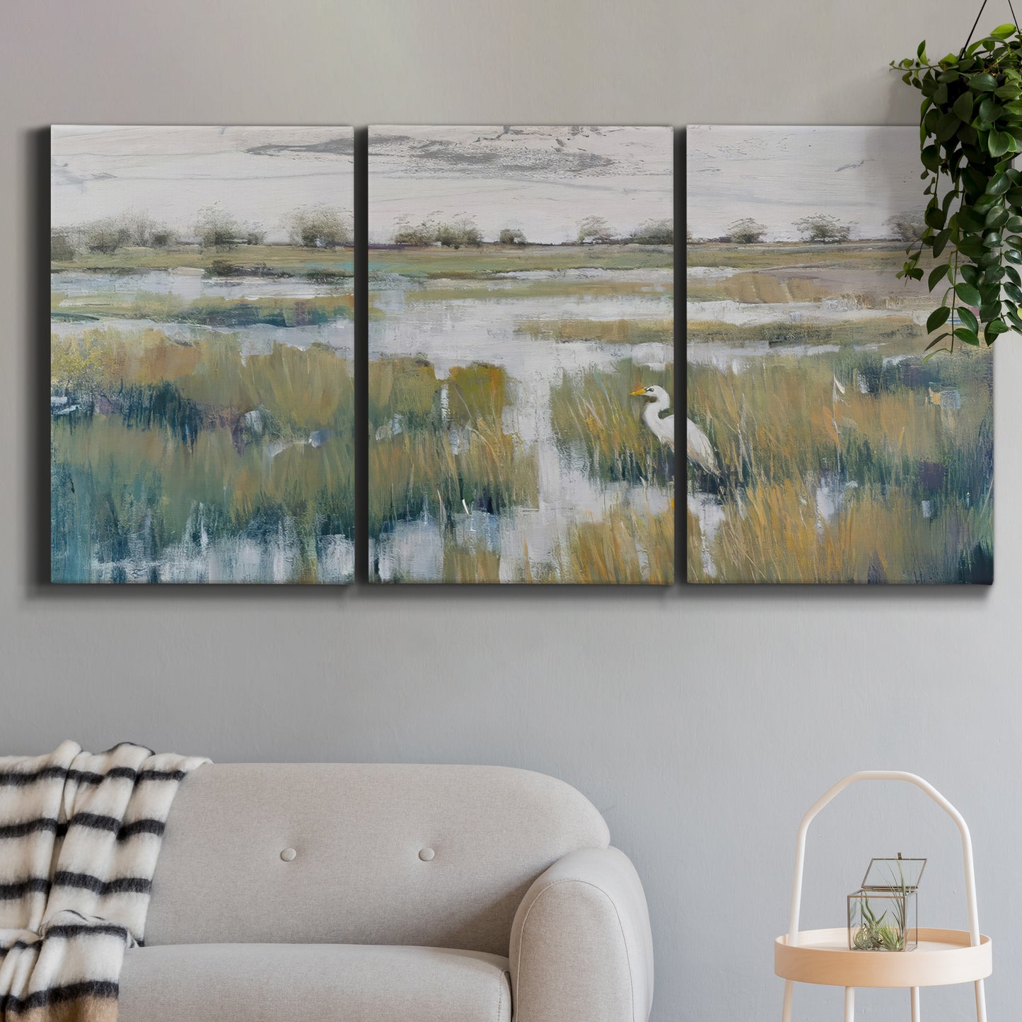Three-panel canvas wall art featuring pastoral marshland landscape, displayed in a modern living room above a sofa.