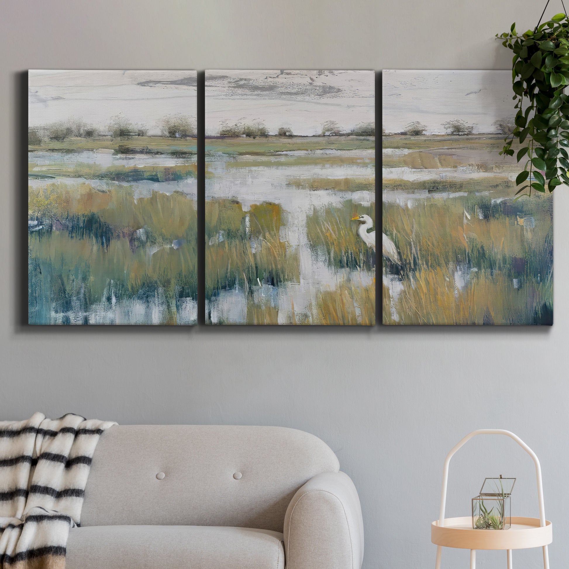 Three-panel canvas wall art featuring pastoral marshland landscape, displayed in a modern living room above a sofa.