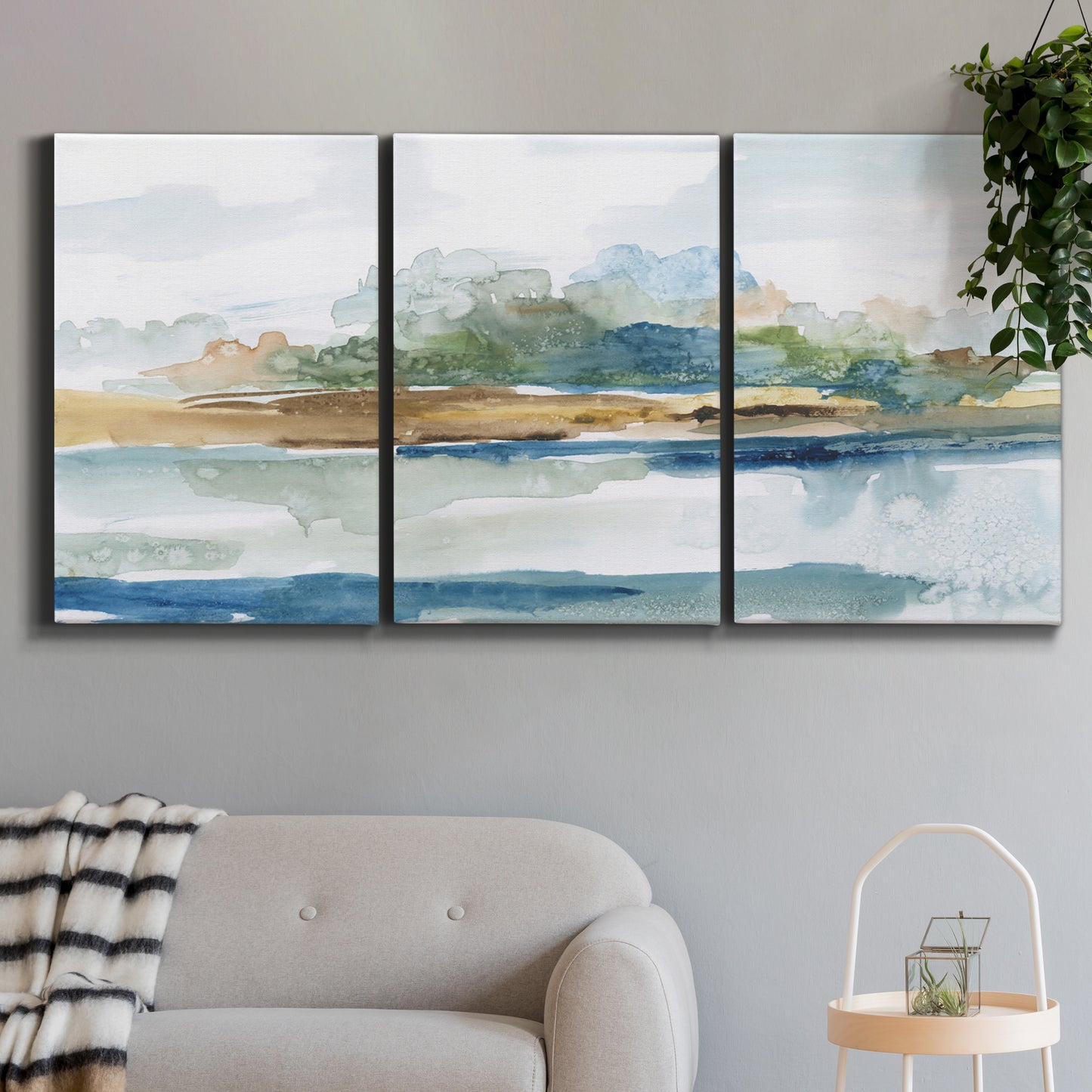 Three-panel canvas wall art featuring flowing blue abstract watercolor, displayed in a modern living room above a sofa.