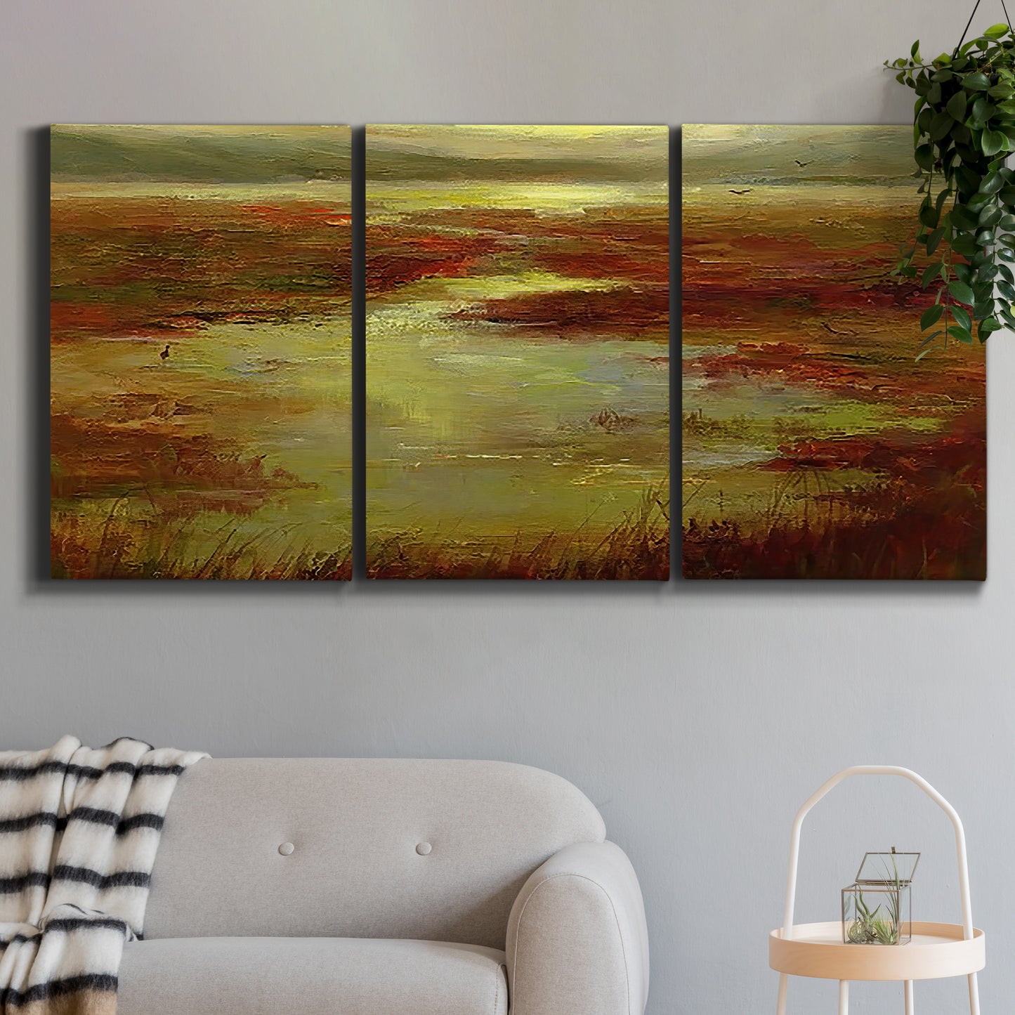 Three-panel canvas wall art featuring coastal shoreline with warm light, displayed in a modern living room above a sofa.