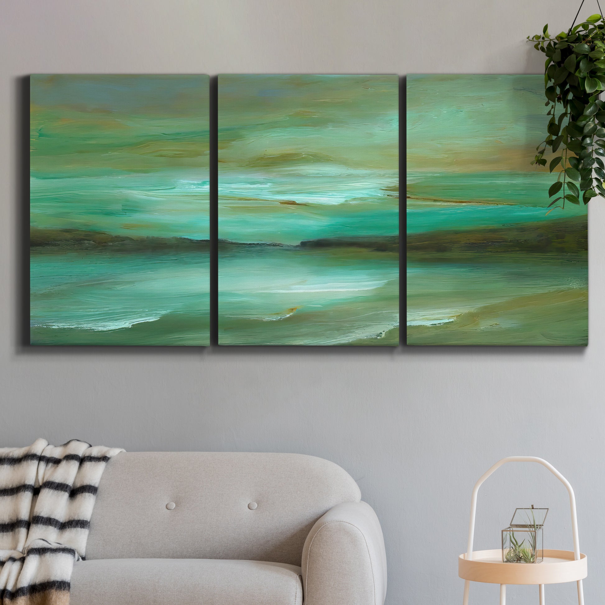 Three-panel canvas wall art featuring hidden coastal cove landscape, displayed in a modern living room above a sofa.