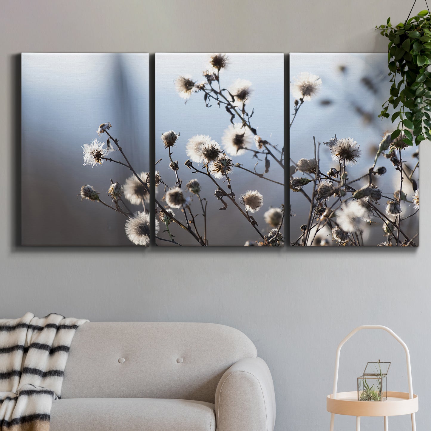 Three-panel canvas wall art featuring delicate spring blossoms on branches, displayed in a modern living room above a sofa.