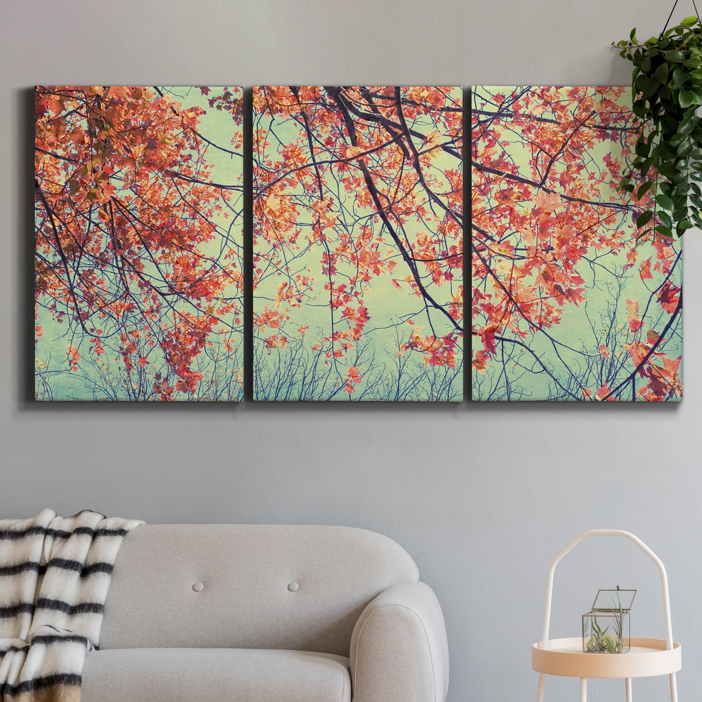 Three-panel canvas wall art featuring autumn foliage landscape photograph, displayed in a modern living room above a sofa.