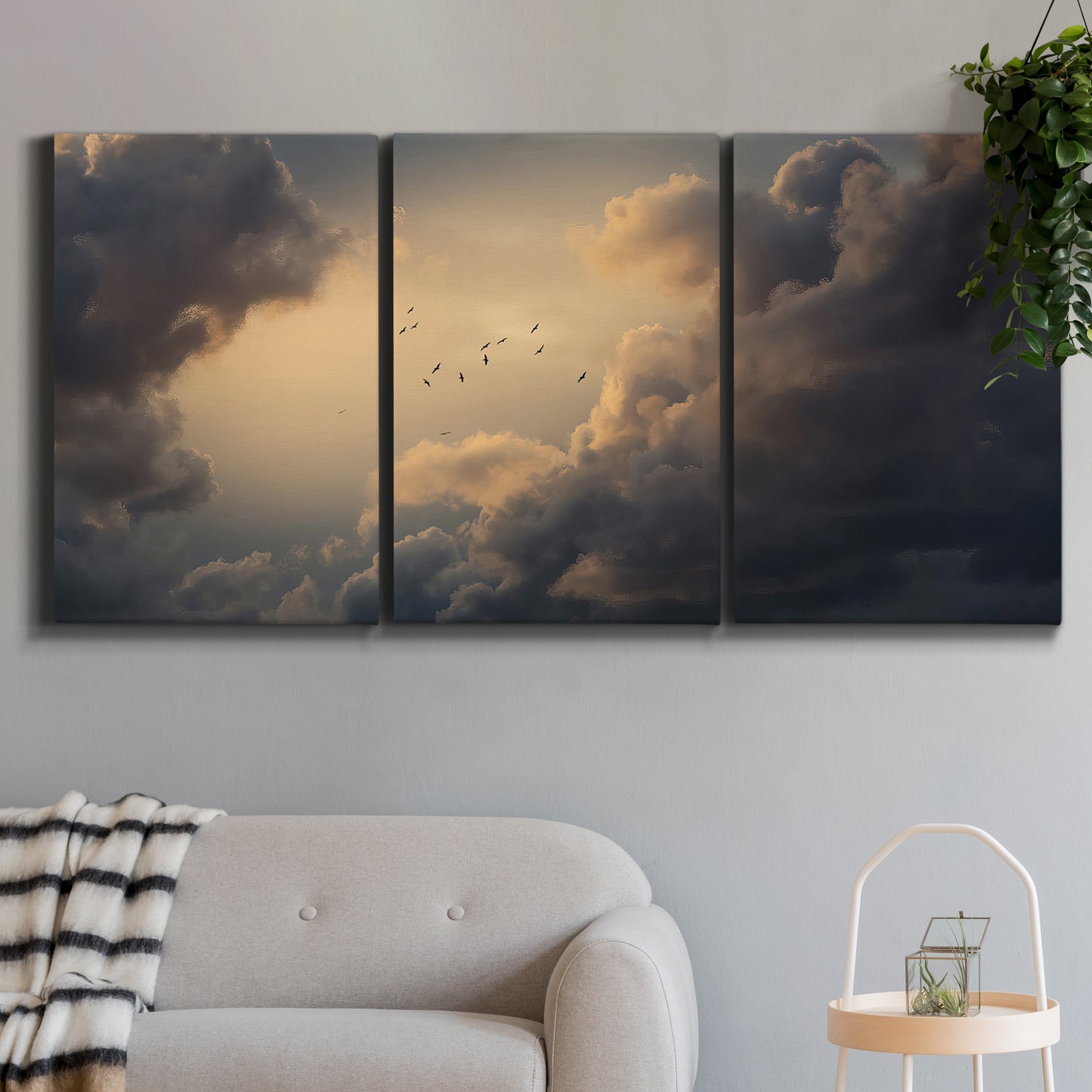 Three-panel canvas wall art featuring surreal floating figures above landscape, displayed in a modern living room above a sofa.