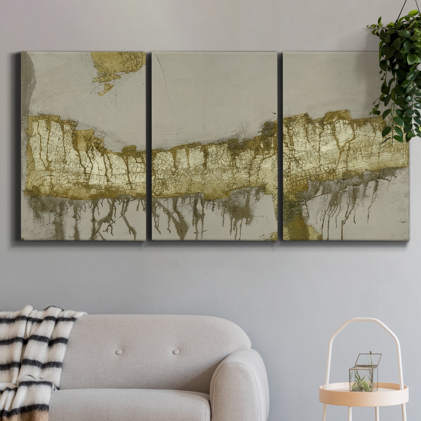 Three-panel canvas wall art featuring gold accented abstract ravine, displayed in a modern living room above a sofa.