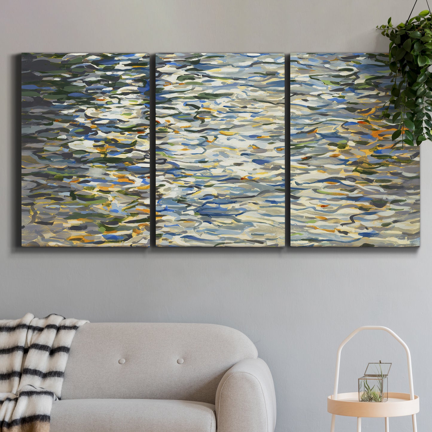 Three-panel canvas wall art featuring abstract water surface reflections, displayed in a modern living room above a sofa.