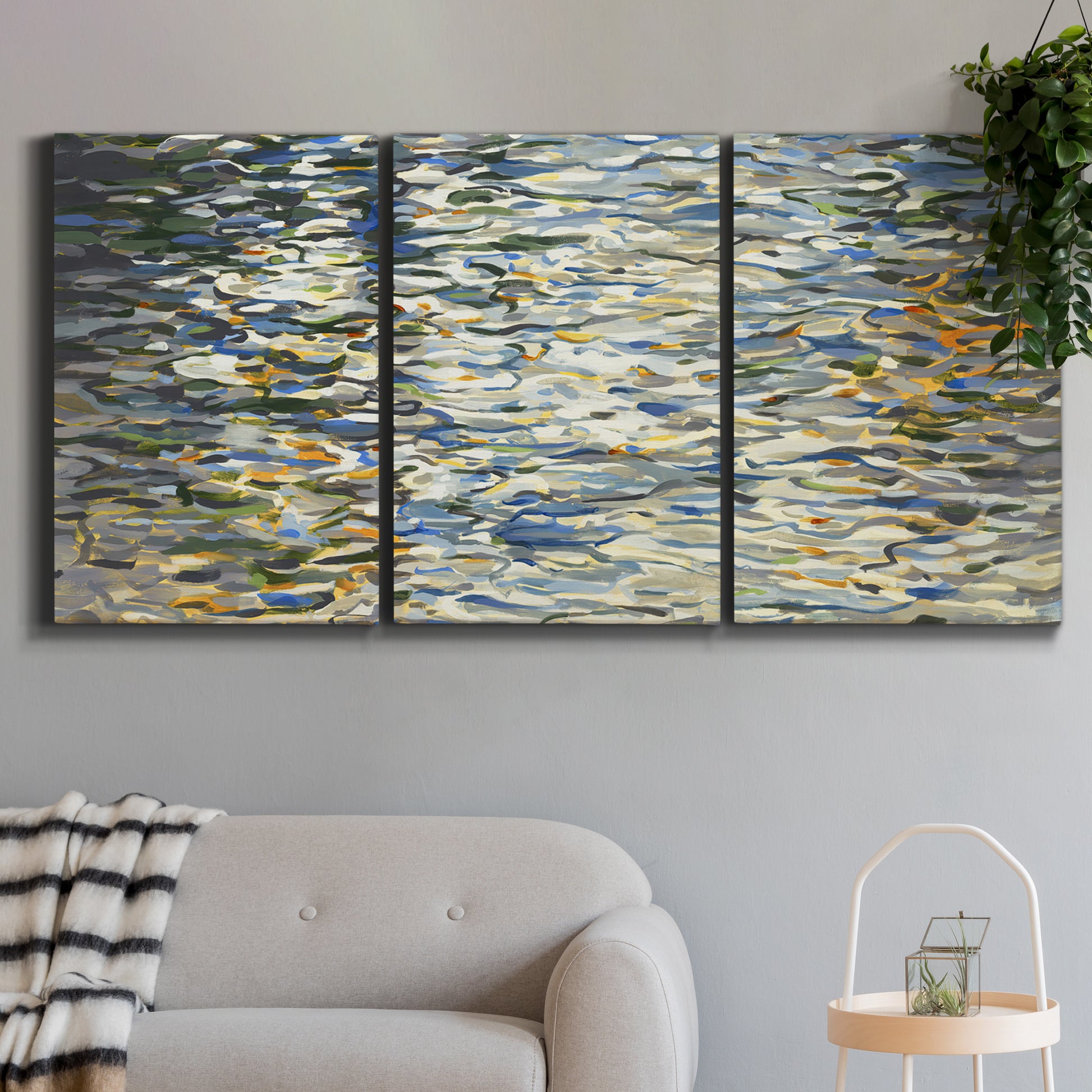 Three-panel canvas wall art featuring abstract water surface reflections, displayed in a modern living room above a sofa.