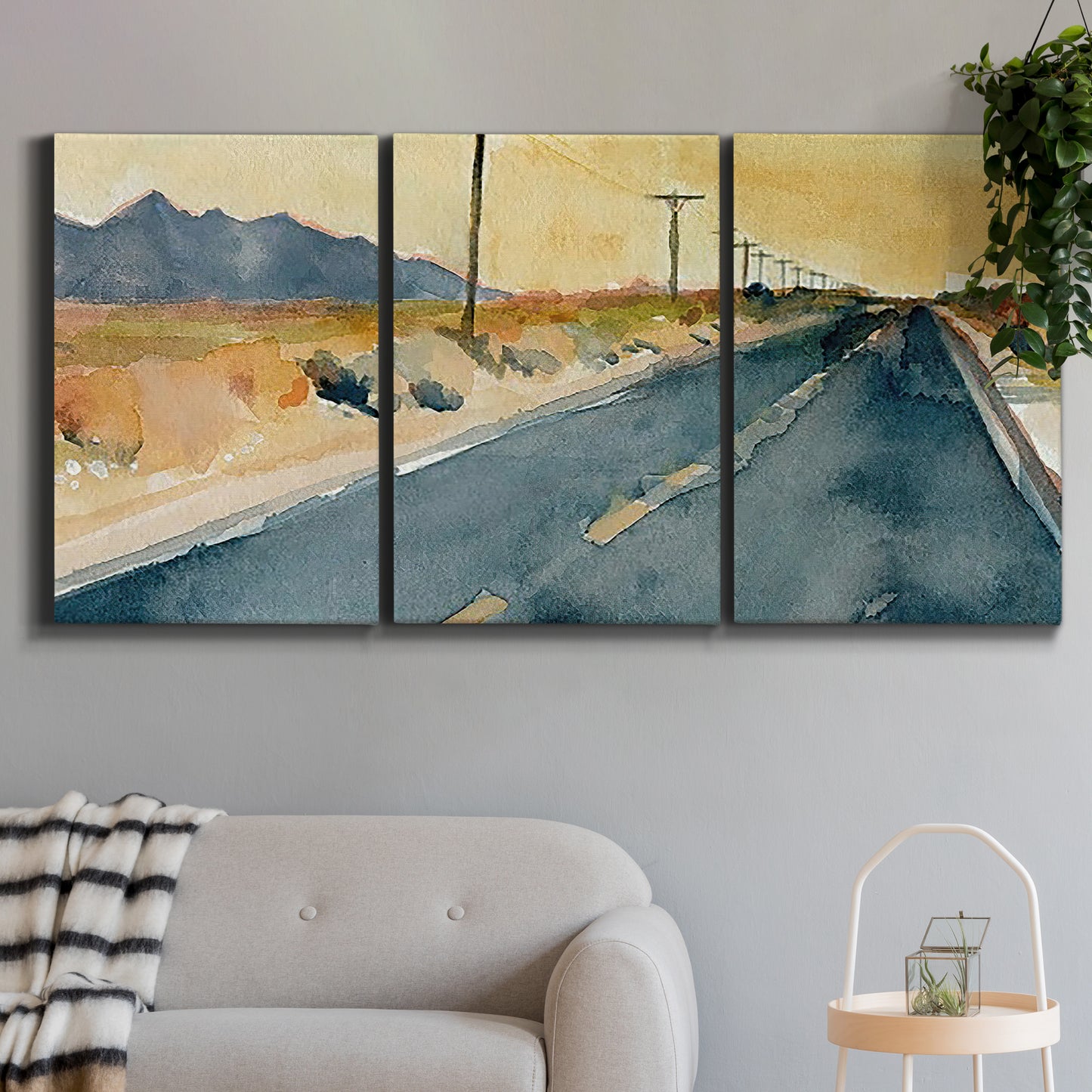 Three-panel canvas wall art featuring empty highway stretching through landscape, displayed in a modern living room above a sofa.