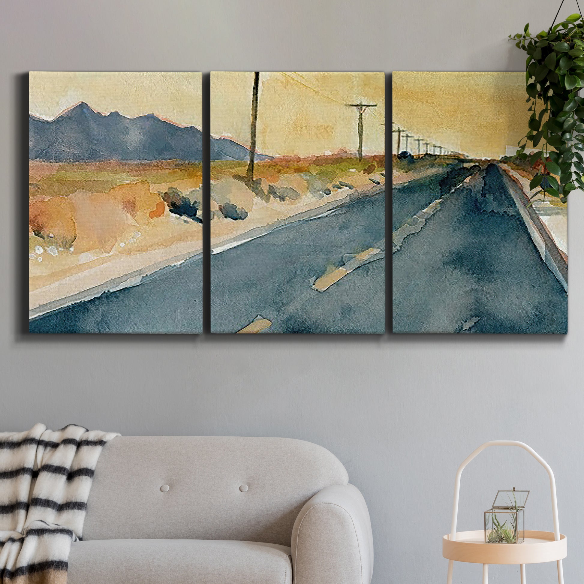 Three-panel canvas wall art featuring empty highway stretching through landscape, displayed in a modern living room above a sofa.