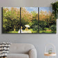 Three-panel canvas wall art featuring lush garden landscape with trees, displayed in a modern living room above a sofa.