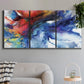 Three-panel canvas wall art featuring vibrant abstract color explosion, displayed in a modern living room above a sofa.