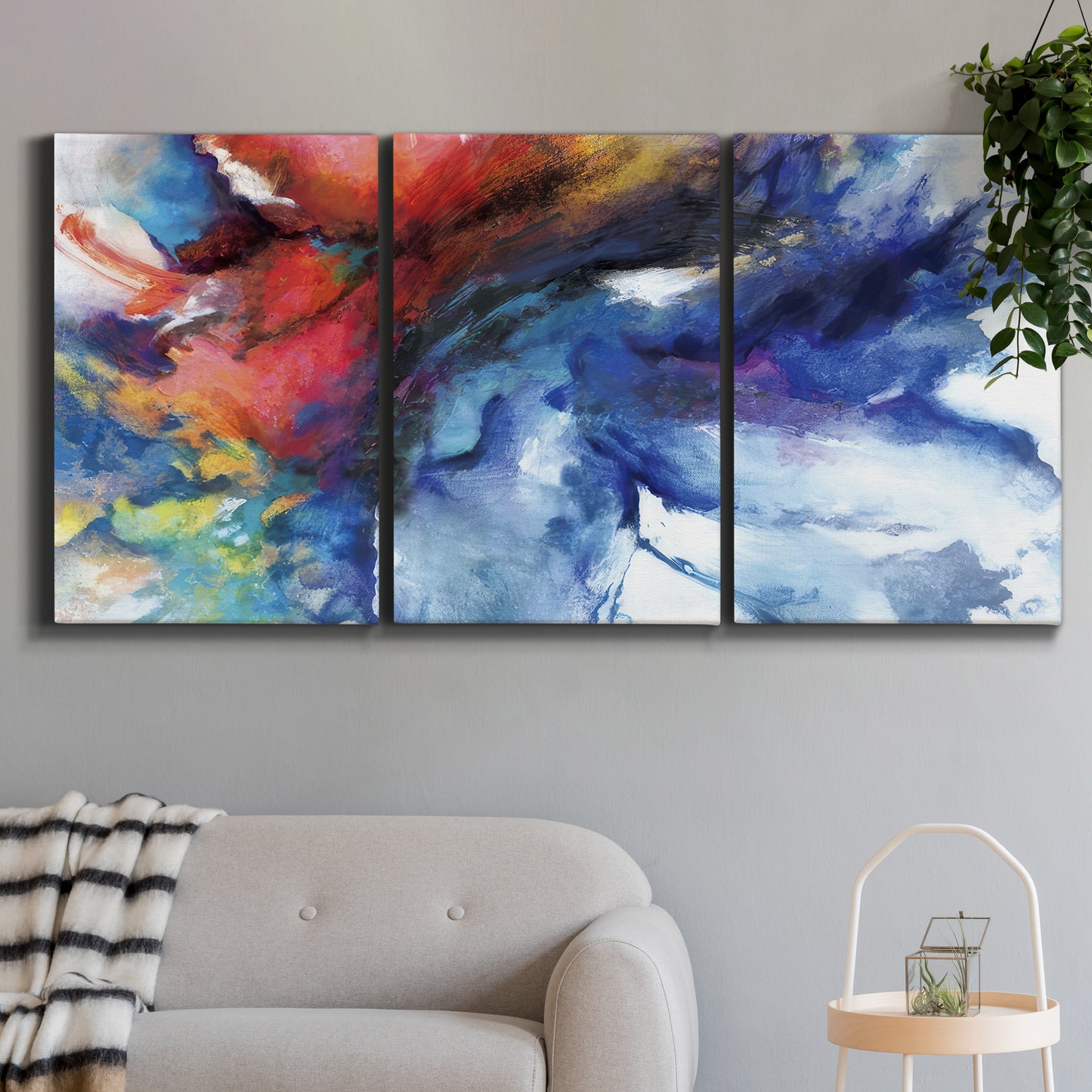 Three-panel canvas wall art featuring vibrant abstract color explosion, displayed in a modern living room above a sofa.