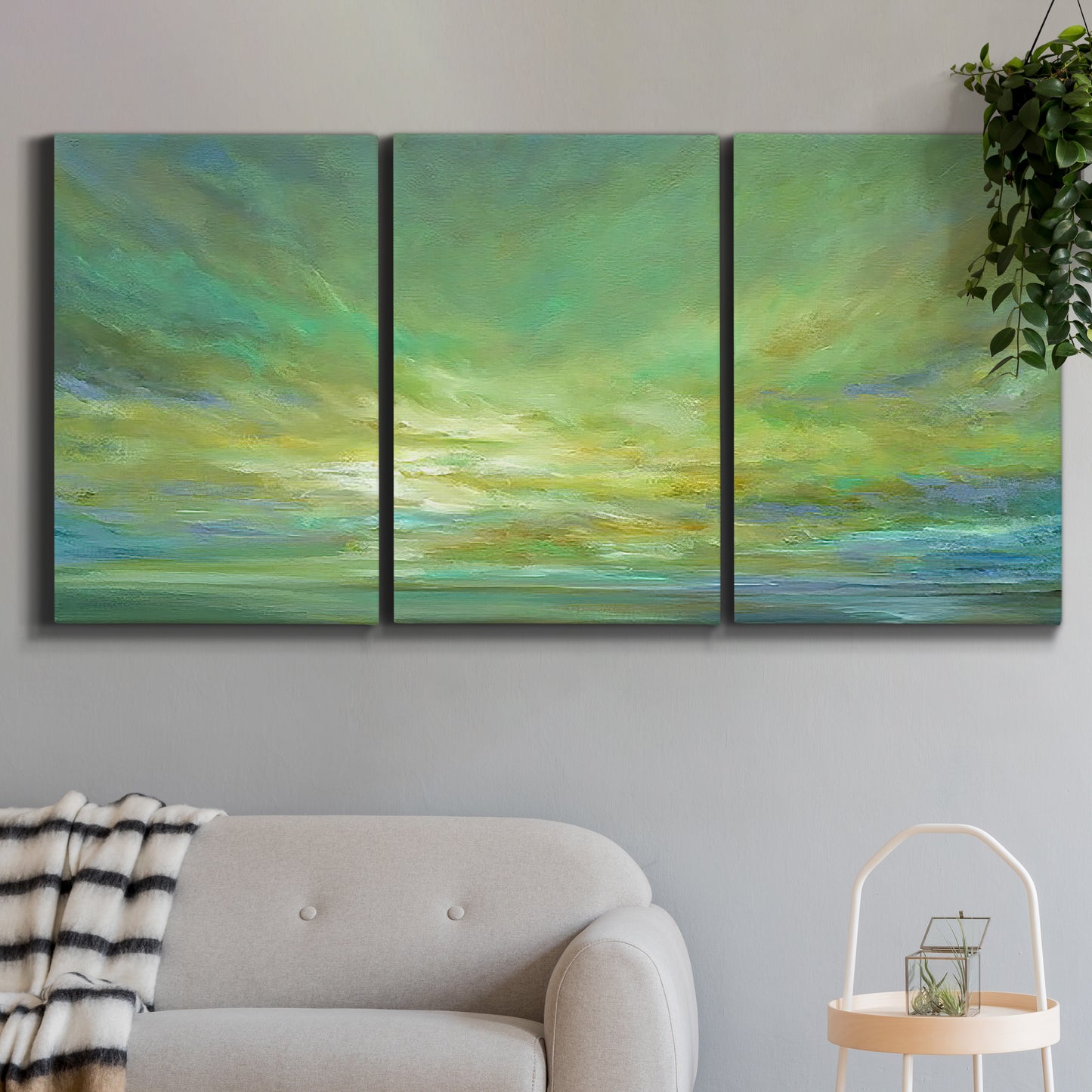 Three-panel canvas wall art featuring coastal shoreline under open sky, displayed in a modern living room above a sofa.