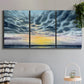 Three-panel canvas wall art featuring tropical coastal sunset over water, displayed in a modern living room above a sofa.