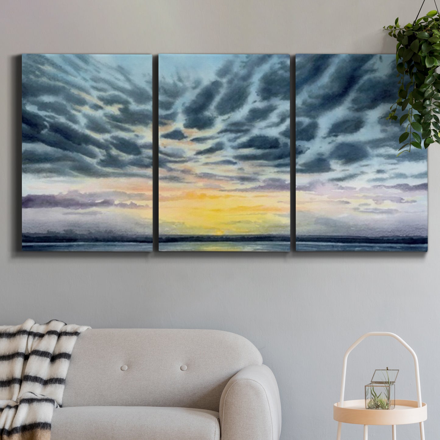 Three-panel canvas wall art featuring tropical coastal sunset over water, displayed in a modern living room above a sofa.