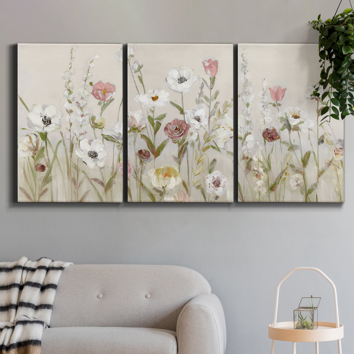 Three-panel canvas wall art featuring loose farmhouse style floral painting, displayed in a modern living room above a sofa.