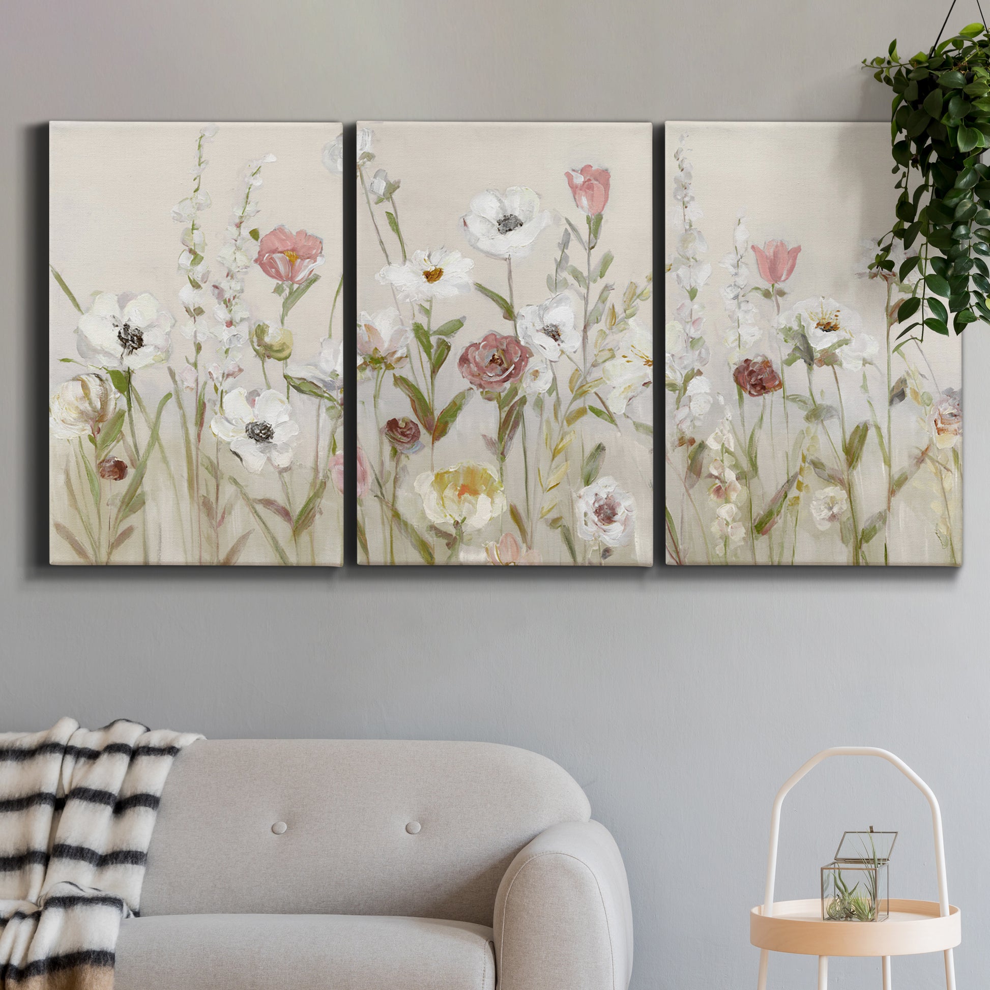 Three-panel canvas wall art featuring loose farmhouse style floral painting, displayed in a modern living room above a sofa.