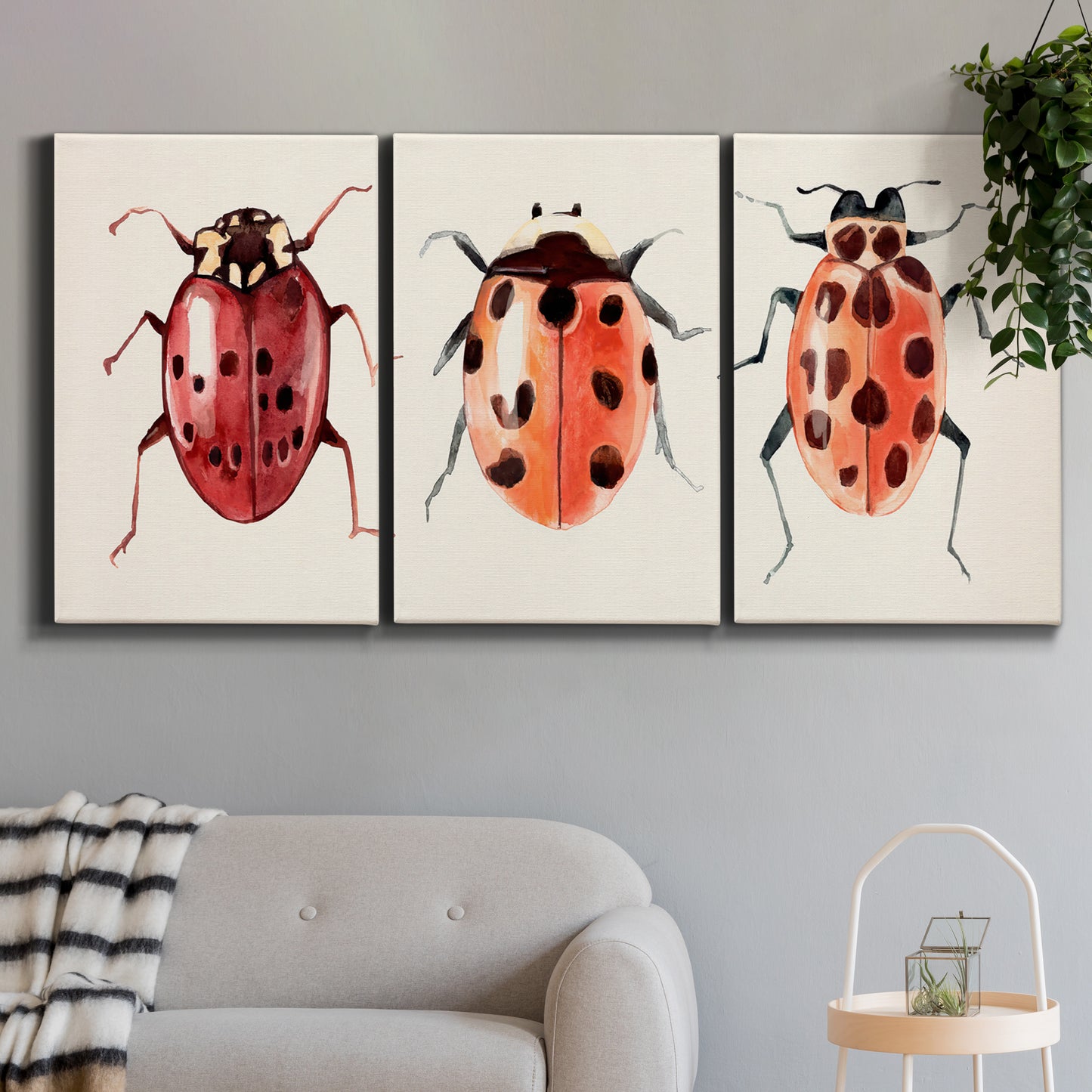 Three-panel canvas wall art featuring ladybugs on green foliage, displayed in a modern living room above a sofa.