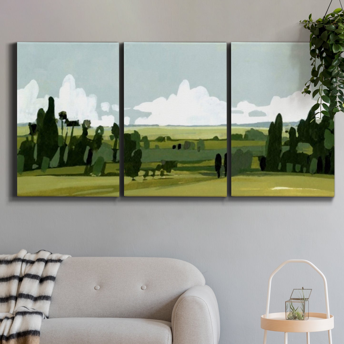 Three-panel canvas wall art featuring lush green summer countryside, displayed in a modern living room above a sofa.