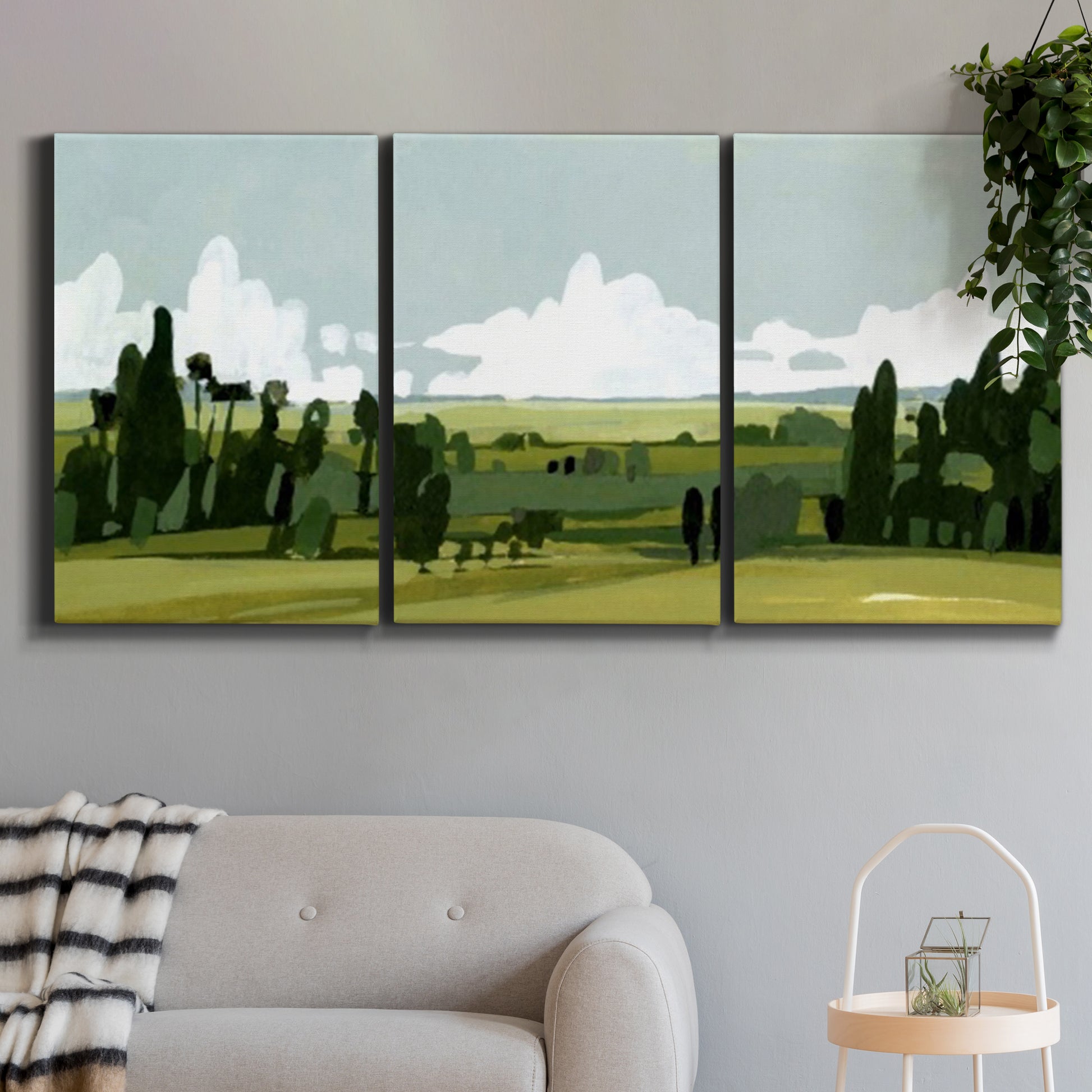 Three-panel canvas wall art featuring lush green summer countryside, displayed in a modern living room above a sofa.