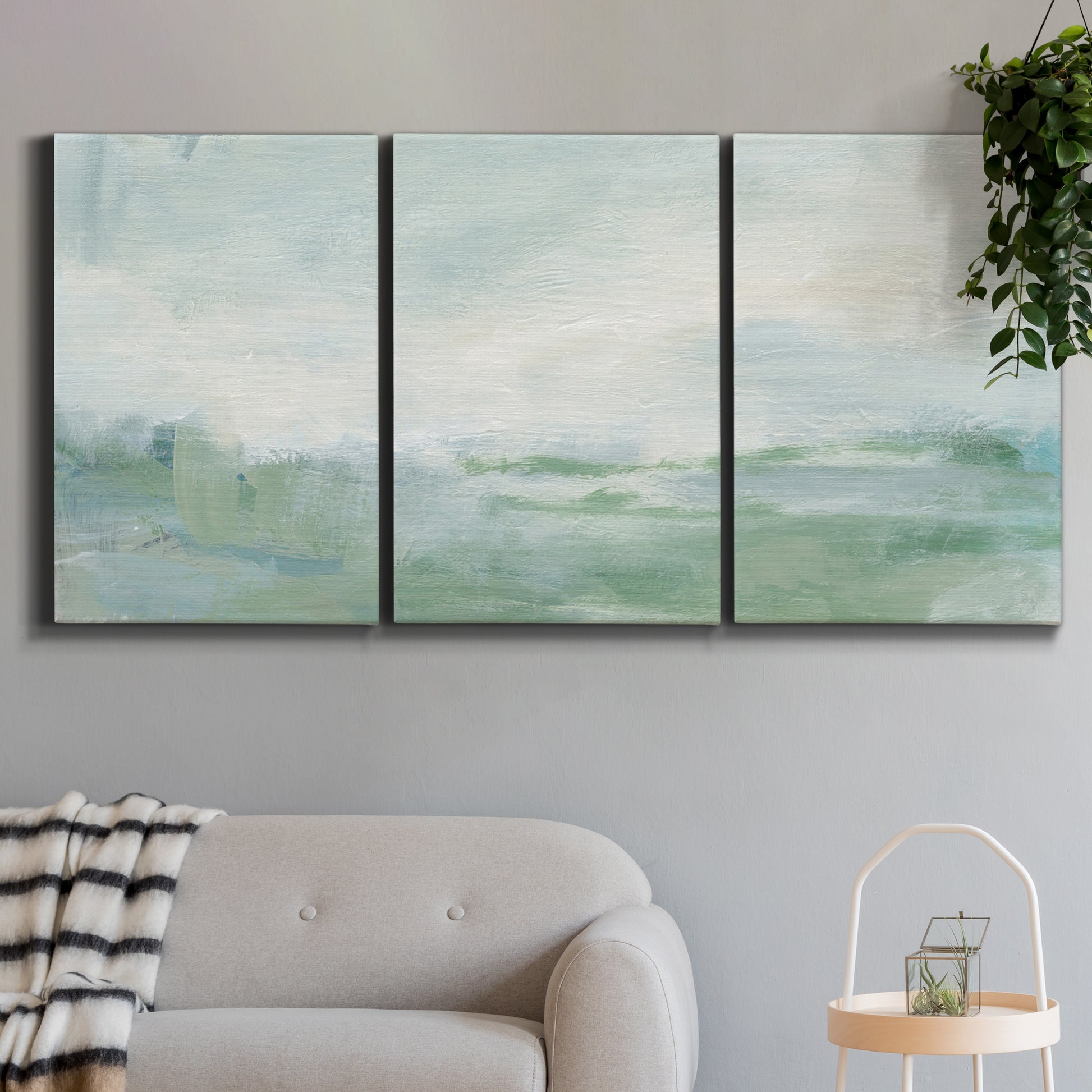 Three-panel canvas wall art featuring soft abstract coastal tones, displayed in a modern living room above a sofa.