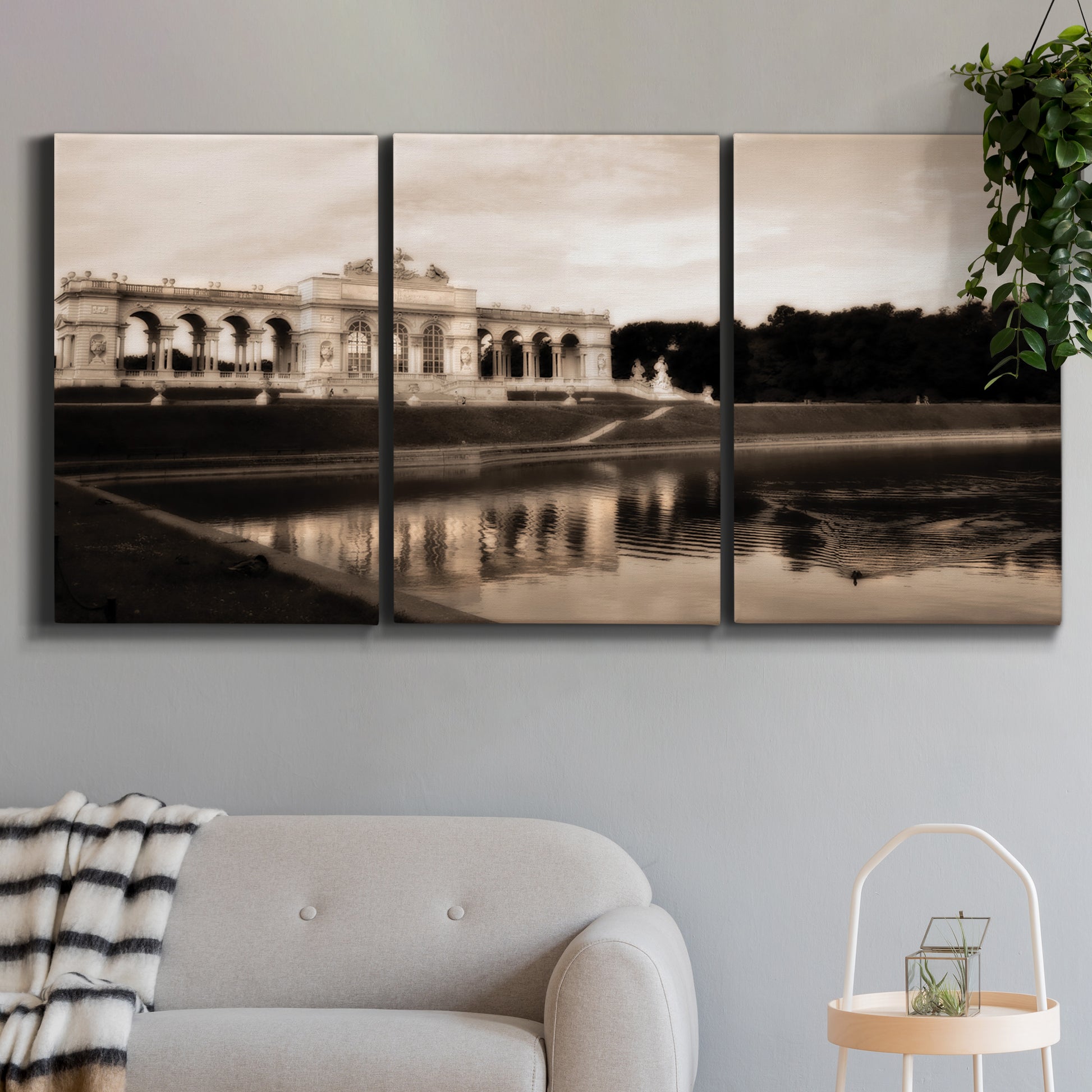 Three-panel canvas wall art featuring monochrome historic pavilion photograph, displayed in a modern living room above a sofa.