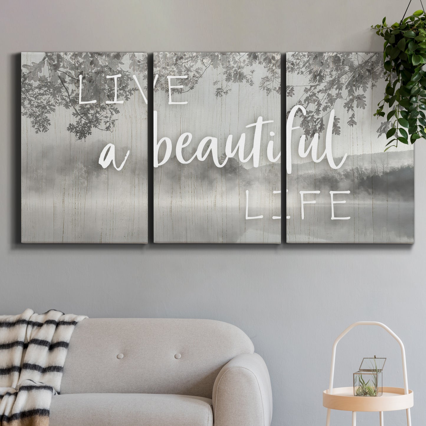 Three-panel canvas wall art featuring uplifting life themed typography, displayed in a modern living room above a sofa.