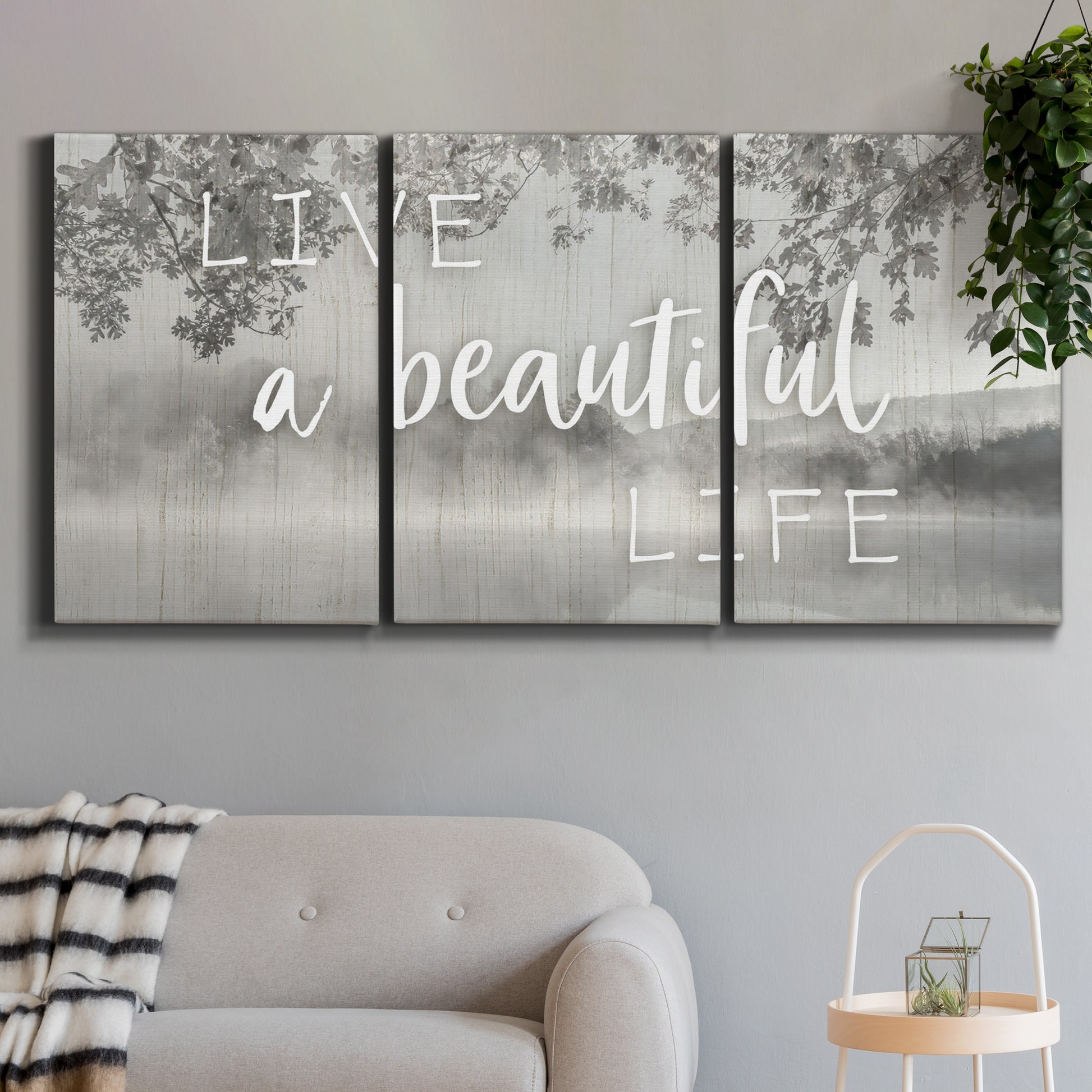 Three-panel canvas wall art featuring uplifting life themed typography, displayed in a modern living room above a sofa.