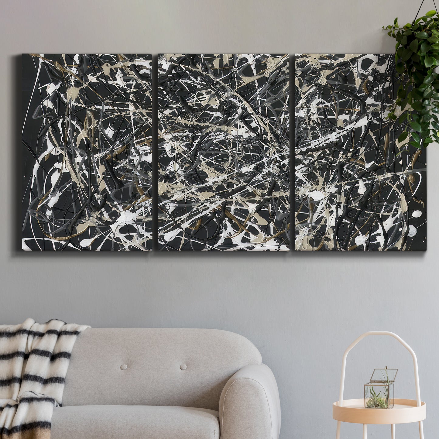 Three-panel canvas wall art featuring energetic expressionist abstract splatter, displayed in a modern living room above a sofa.